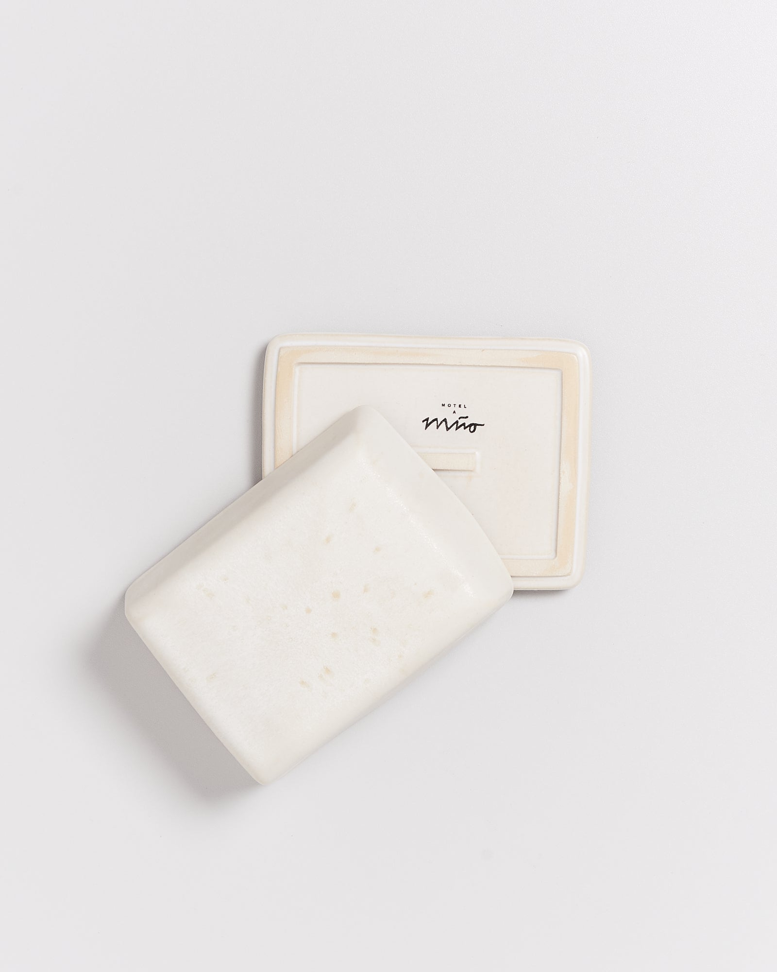 Weiße Seife auf einer Seifenschale mit der Aufschrift "Hotel Miró", auf einem weißen Hintergrund.