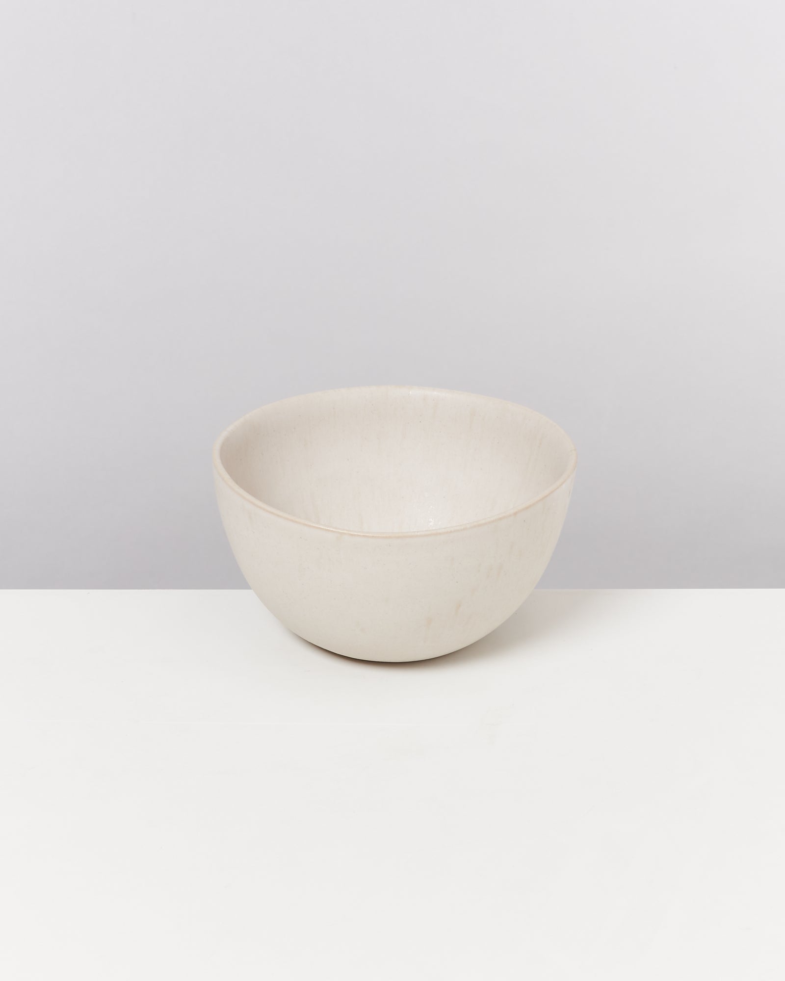 Beige Schüssel auf einem weißen Tisch vor einem hellgrauen Hintergrund.
