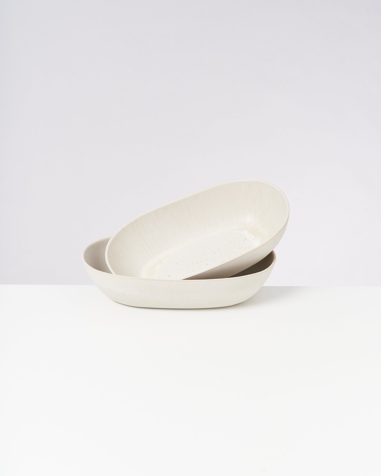 Zwei übereinander gestapelte, weiße, ovale Schalen auf einem weißen Hintergrund.