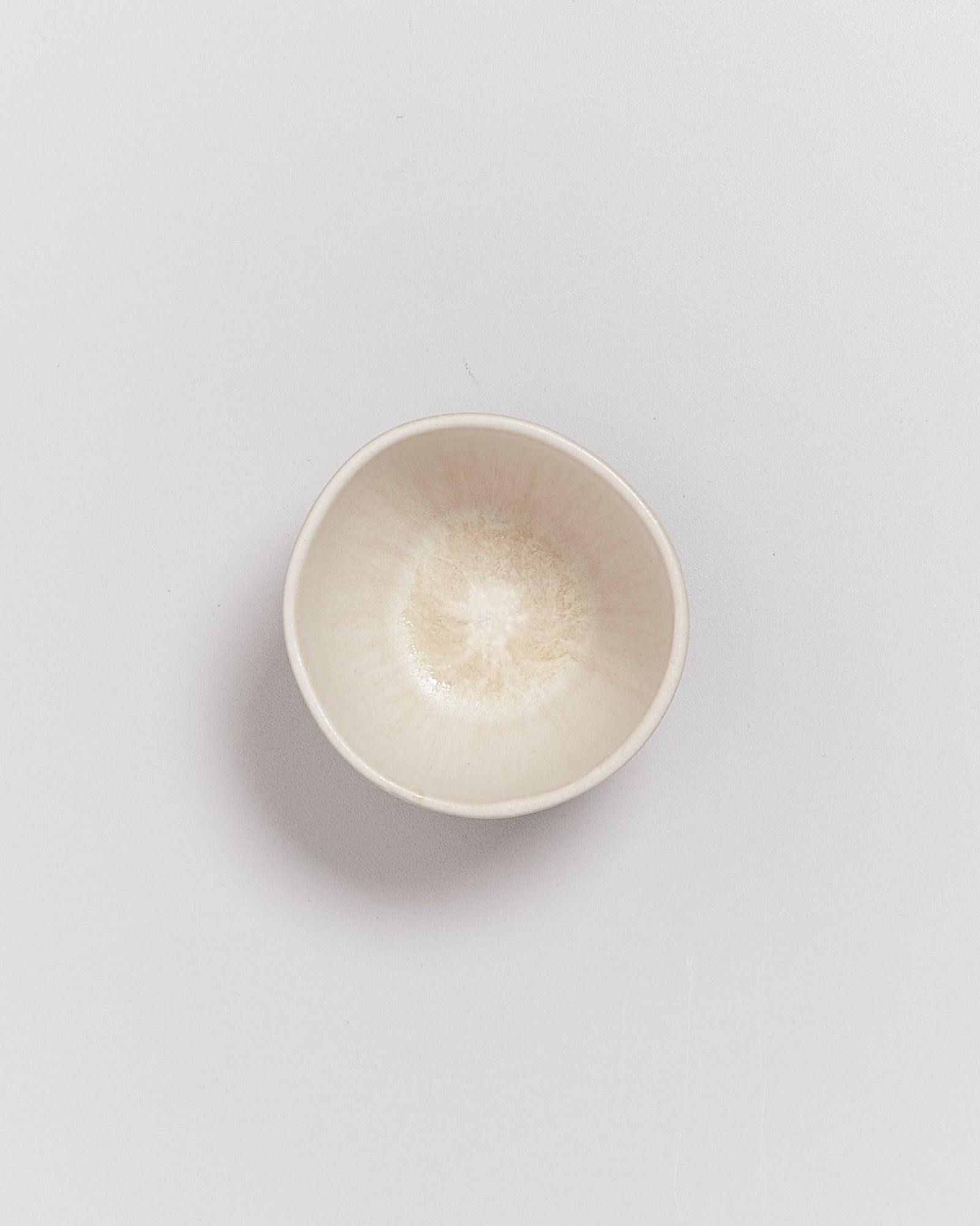 Kleine, cremefarbene Keramikschale auf einem weißen Hintergrund.