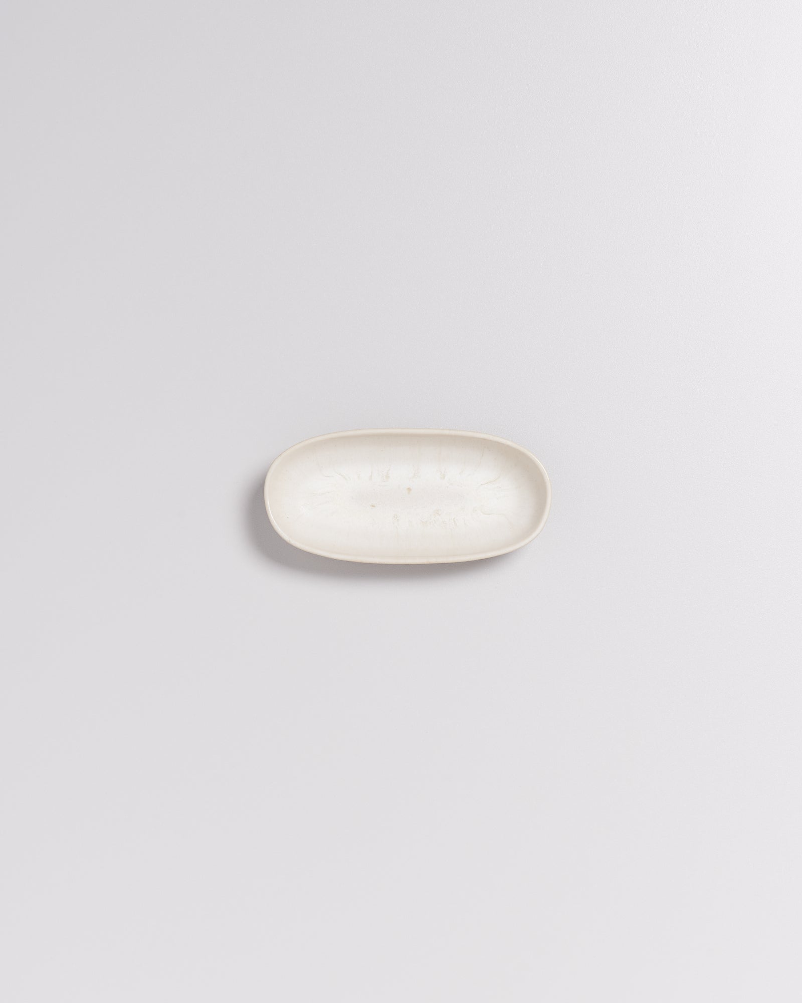 Ein ovaler, cremefarbener Ceramic-Seifenteller auf einem hellgrauen Hintergrund.