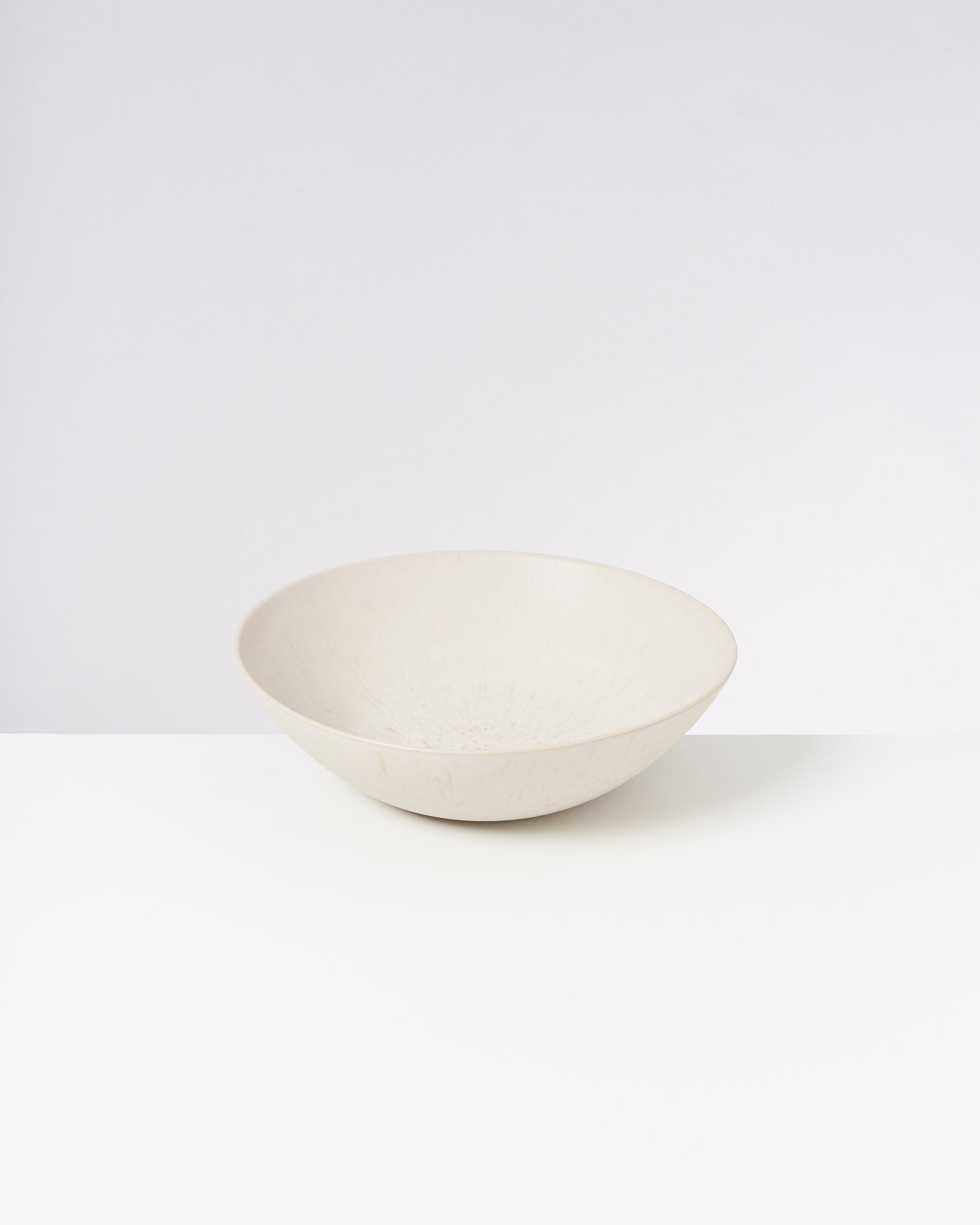 Beiger Keramikteller auf weißem Hintergrund.