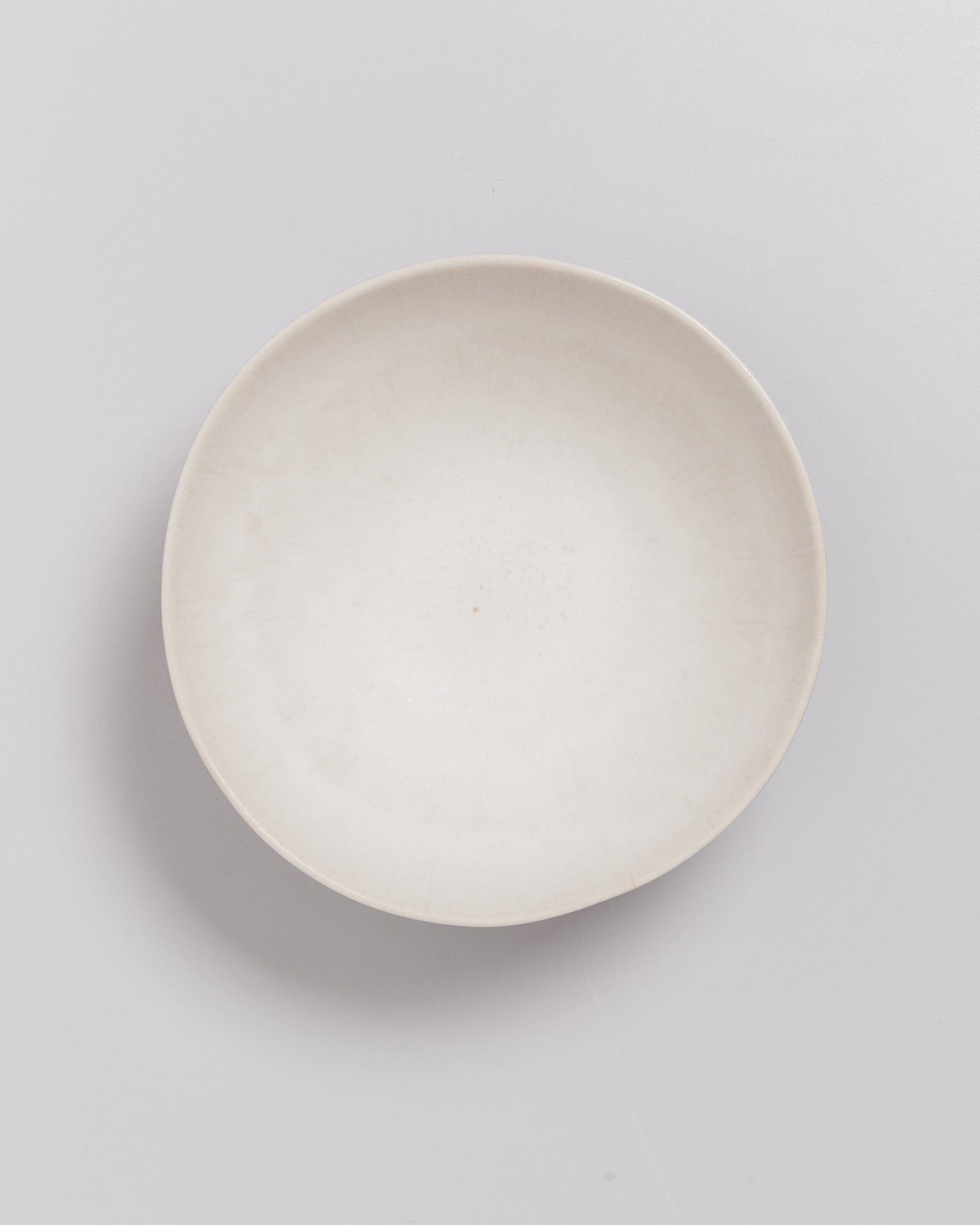 Weißer, leerer Teller auf weißem Hintergrund, von oben fotografiert.
