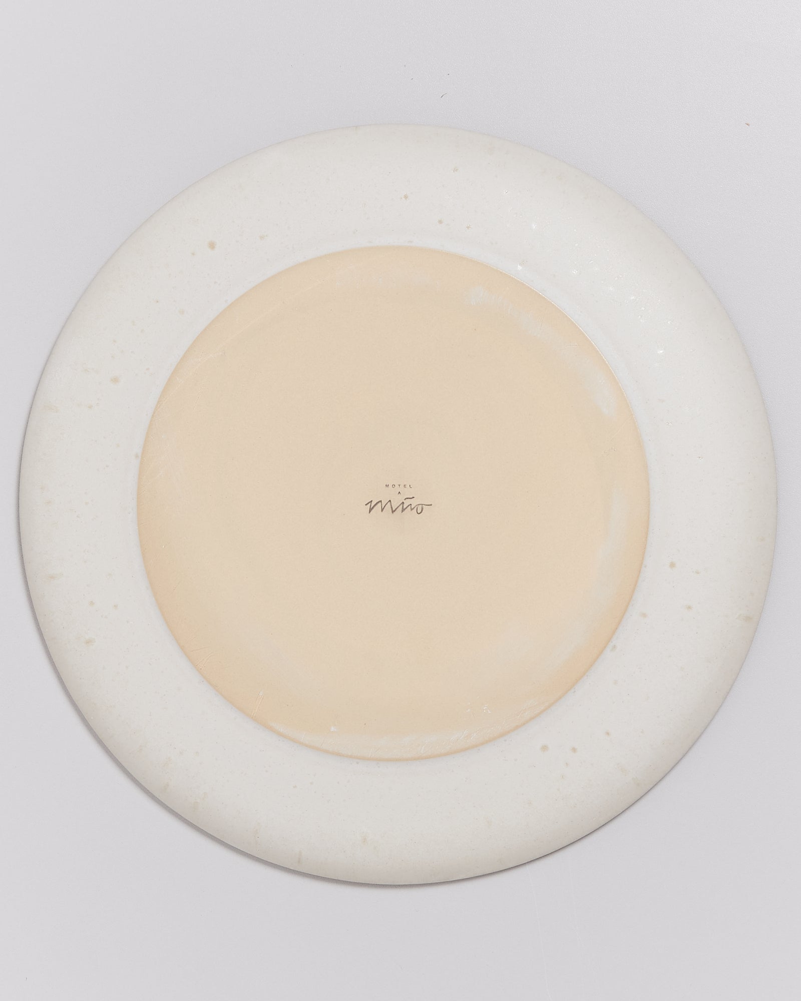 Rückseite eines Tellers mit der Aufschrift "Hotel Miro" auf cremeweißem Hintergrund.