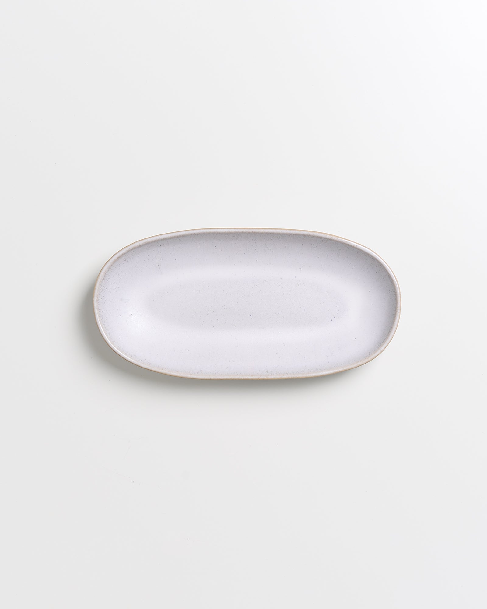 Weiße, ovale Keramikplatte auf einem weißen Hintergrund.