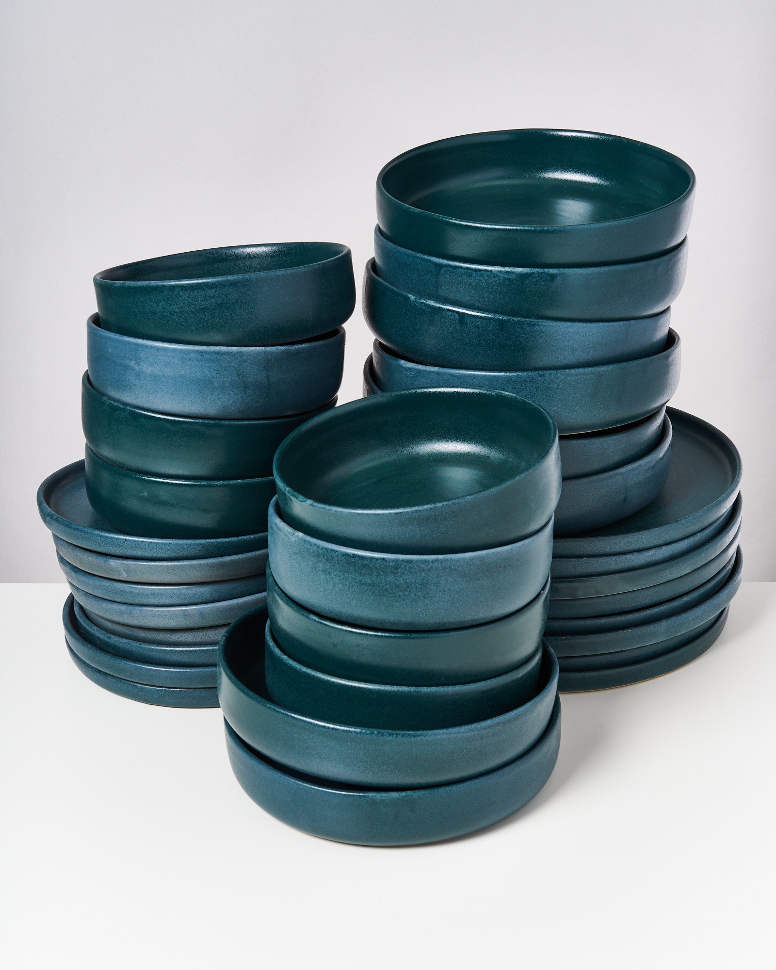 Mehrere gestapelte Stapel blauer Keramikteller auf weißem Hintergrund.
