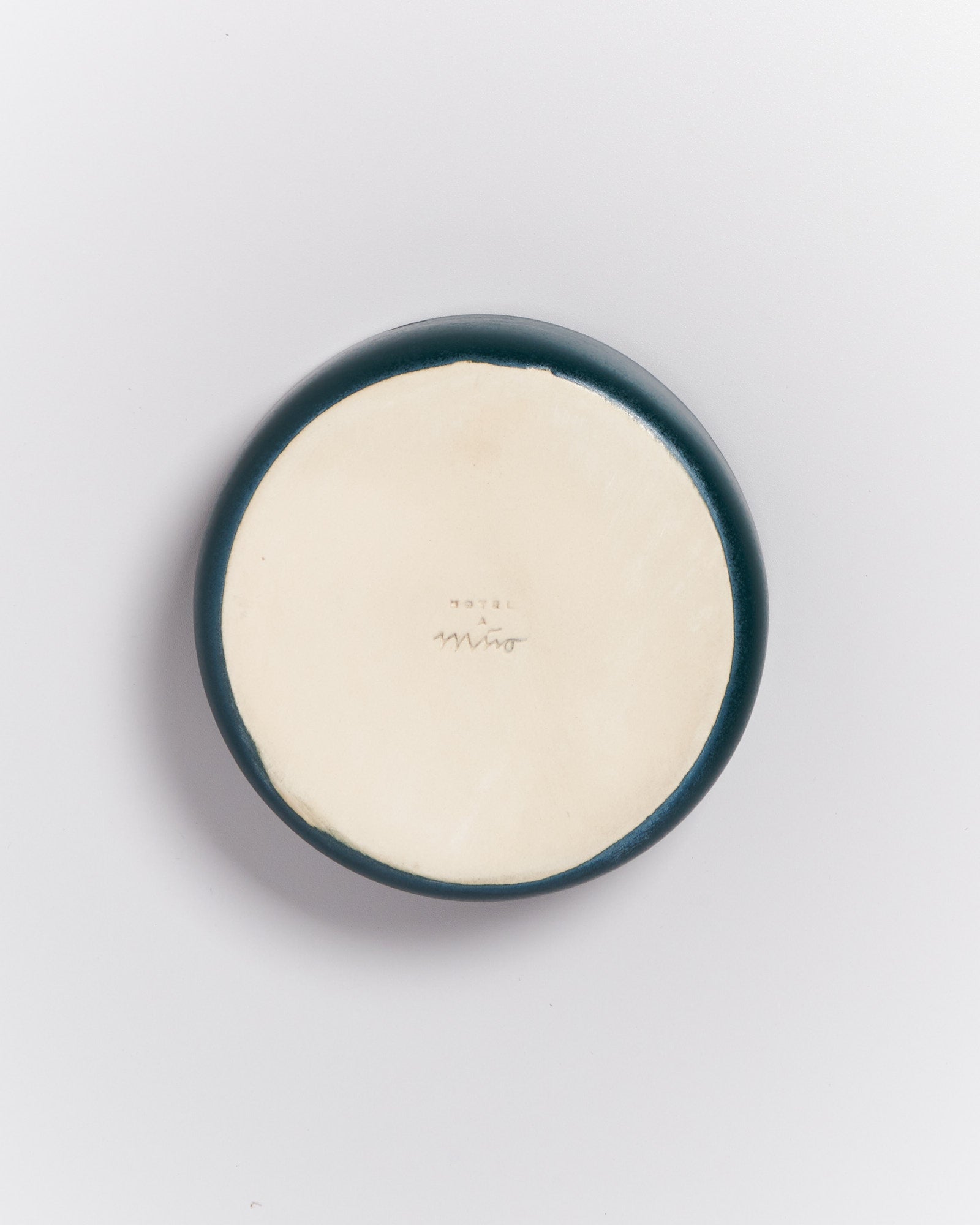 Runder Keramikteller mit dunklem Rand auf weißem Hintergrund, mit einer kleinen Beschriftung in der Mitte.