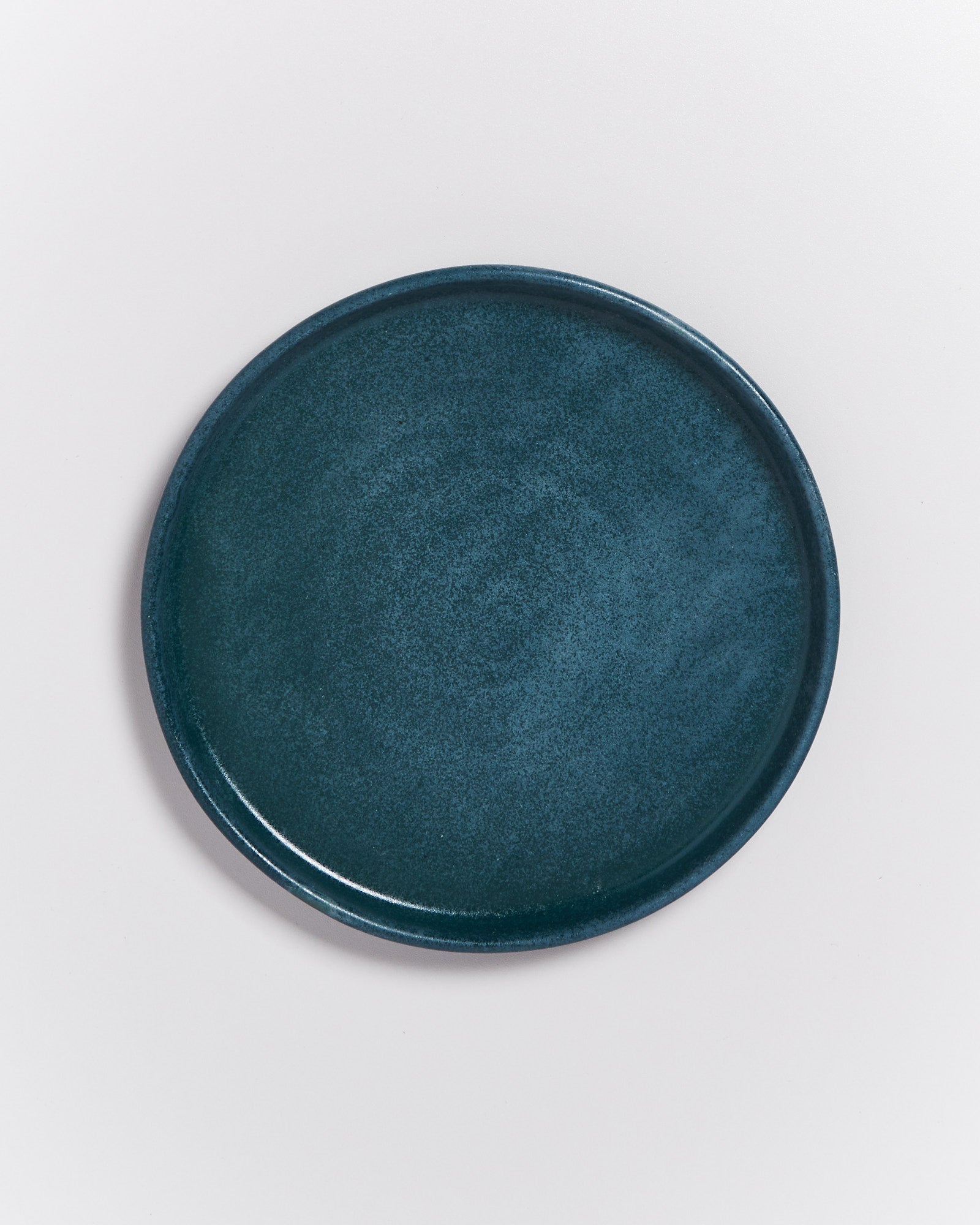 Dunkelblauer Teller auf hellem Hintergrund aus der Vogelperspektive.