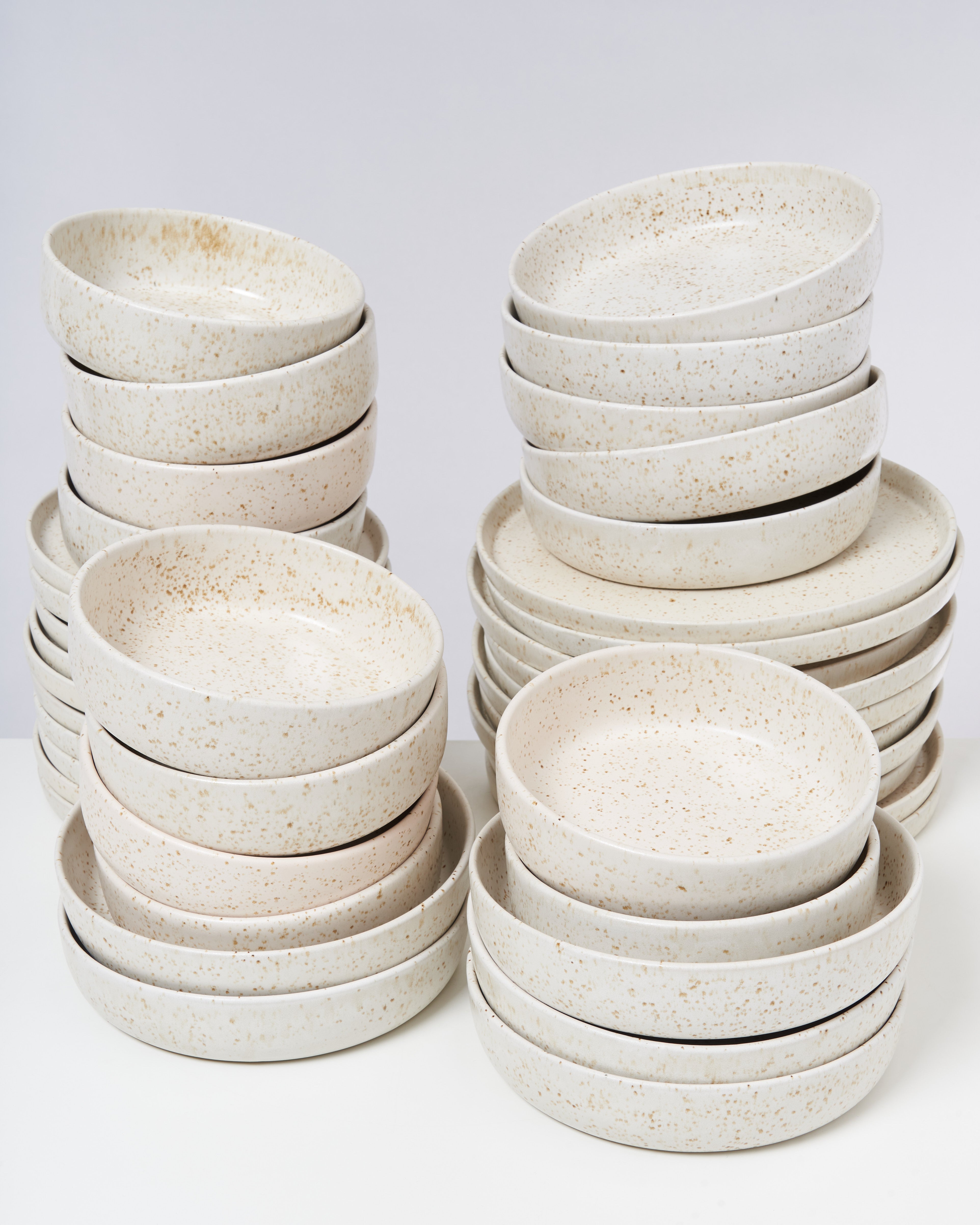 Mehrere Stapel von keramikartigen Schüsseln mit gesprenkeltem Muster auf einer weißen Fläche.