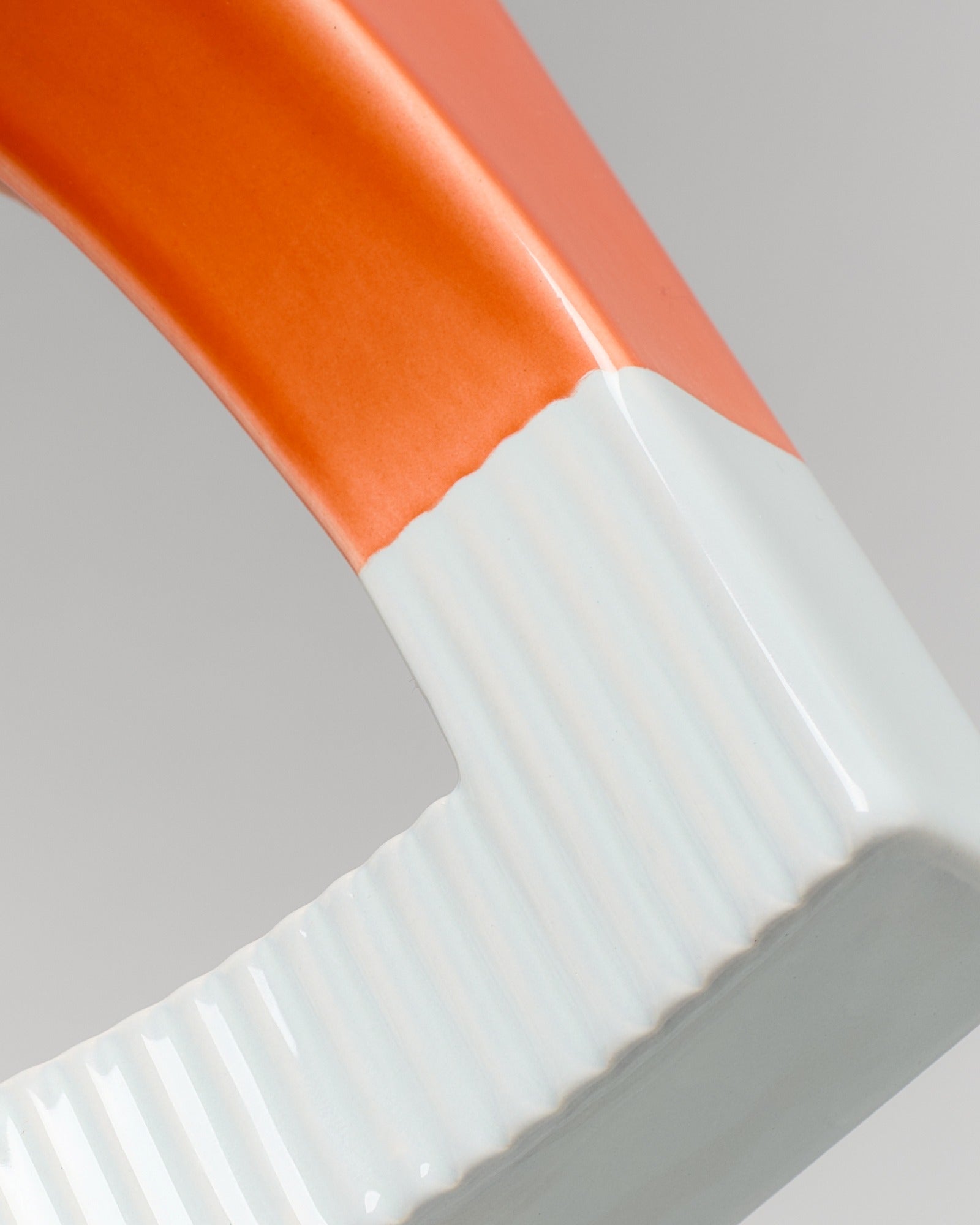 Nahaufnahme eines orange-weißen Keramikobjekts mit geriffelter Oberfläche.
