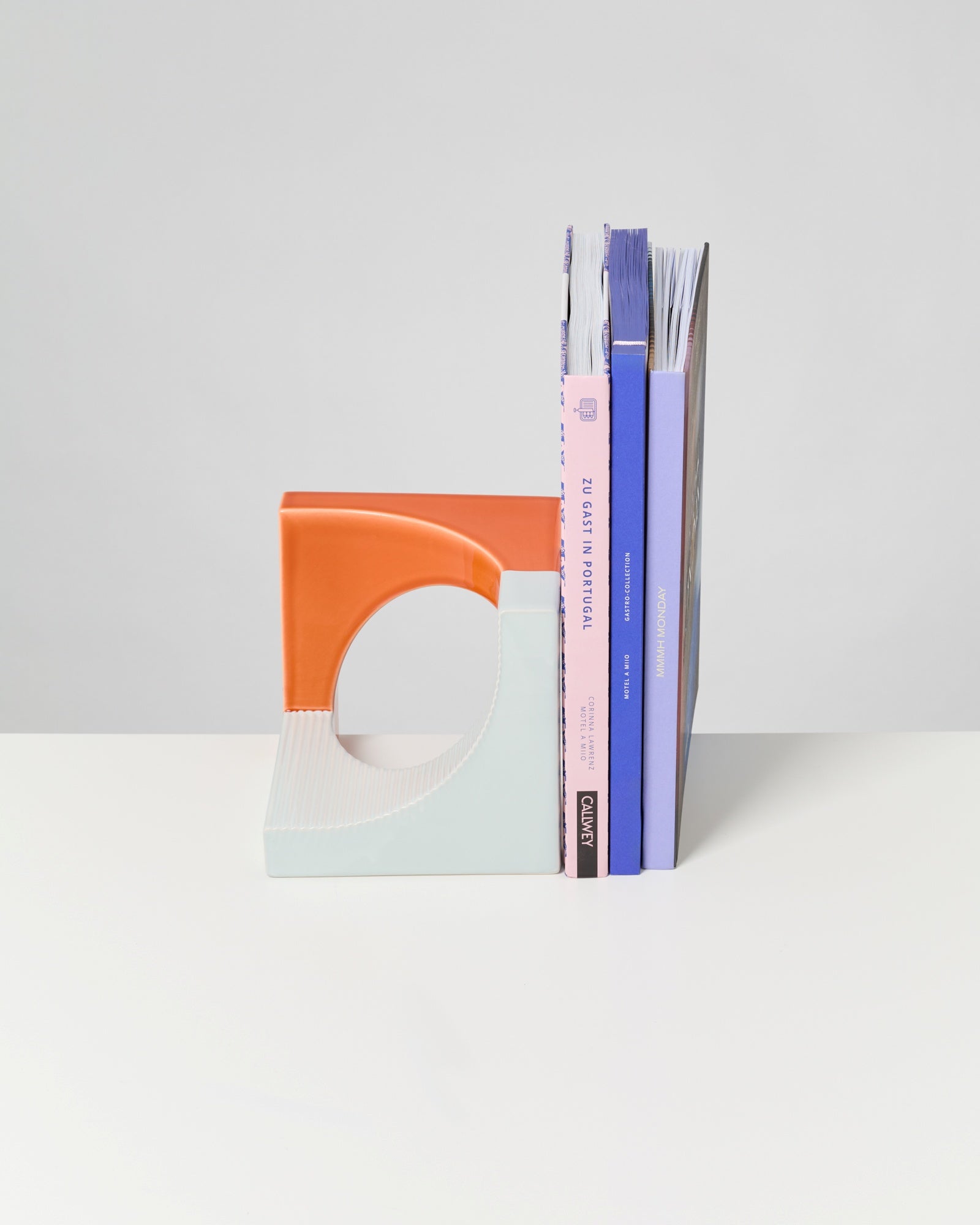 Bücher aufrecht gehalten von buntem Buchstützen-Set in geometrischem Design auf weißem Hintergrund.
