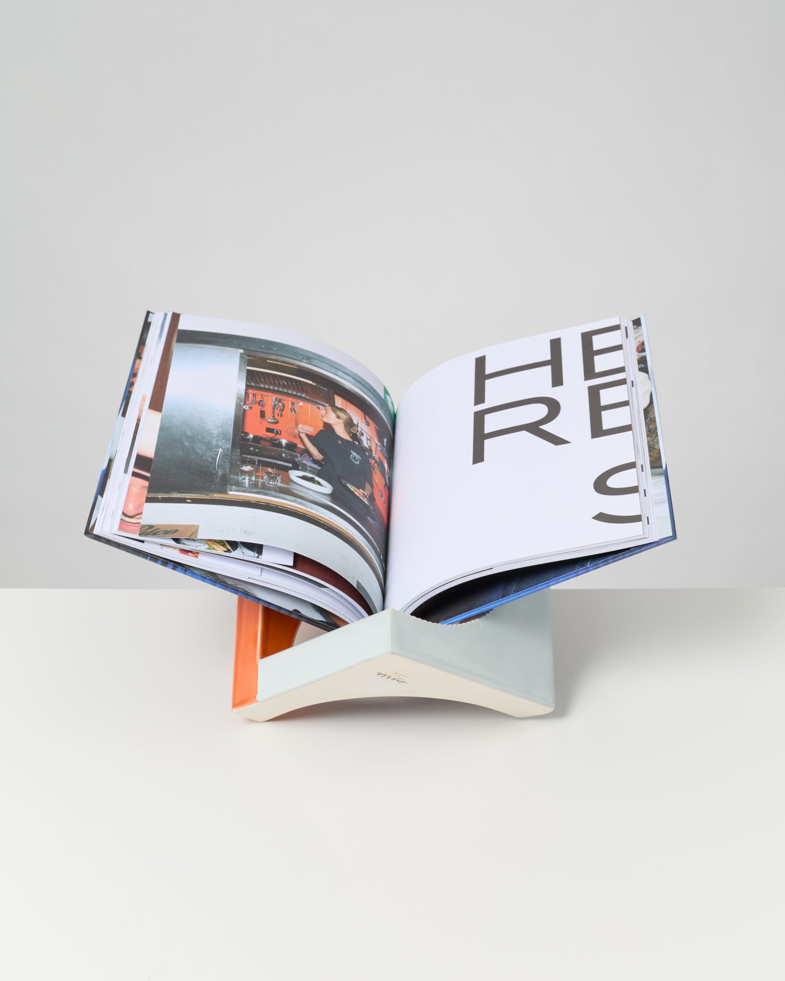 Ein aufgeschlagenes Buch mit großem Text und einem Foto, das auf einem modernen Buchhalter steht.