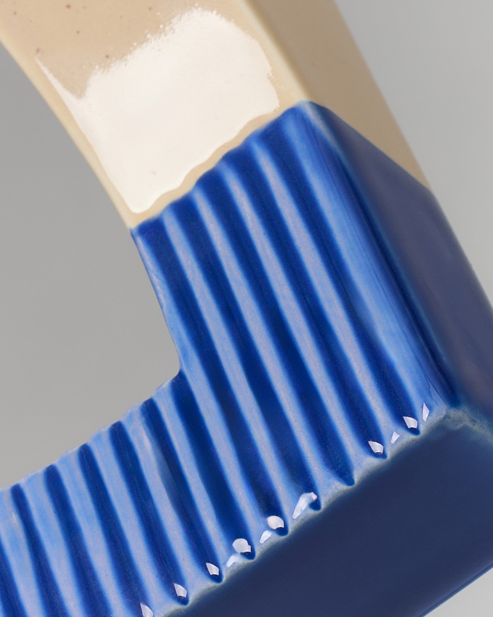 Nahaufnahme einer blau gerippten, rechteckigen Keramikform mit beigem und weißem Farbverlauf.