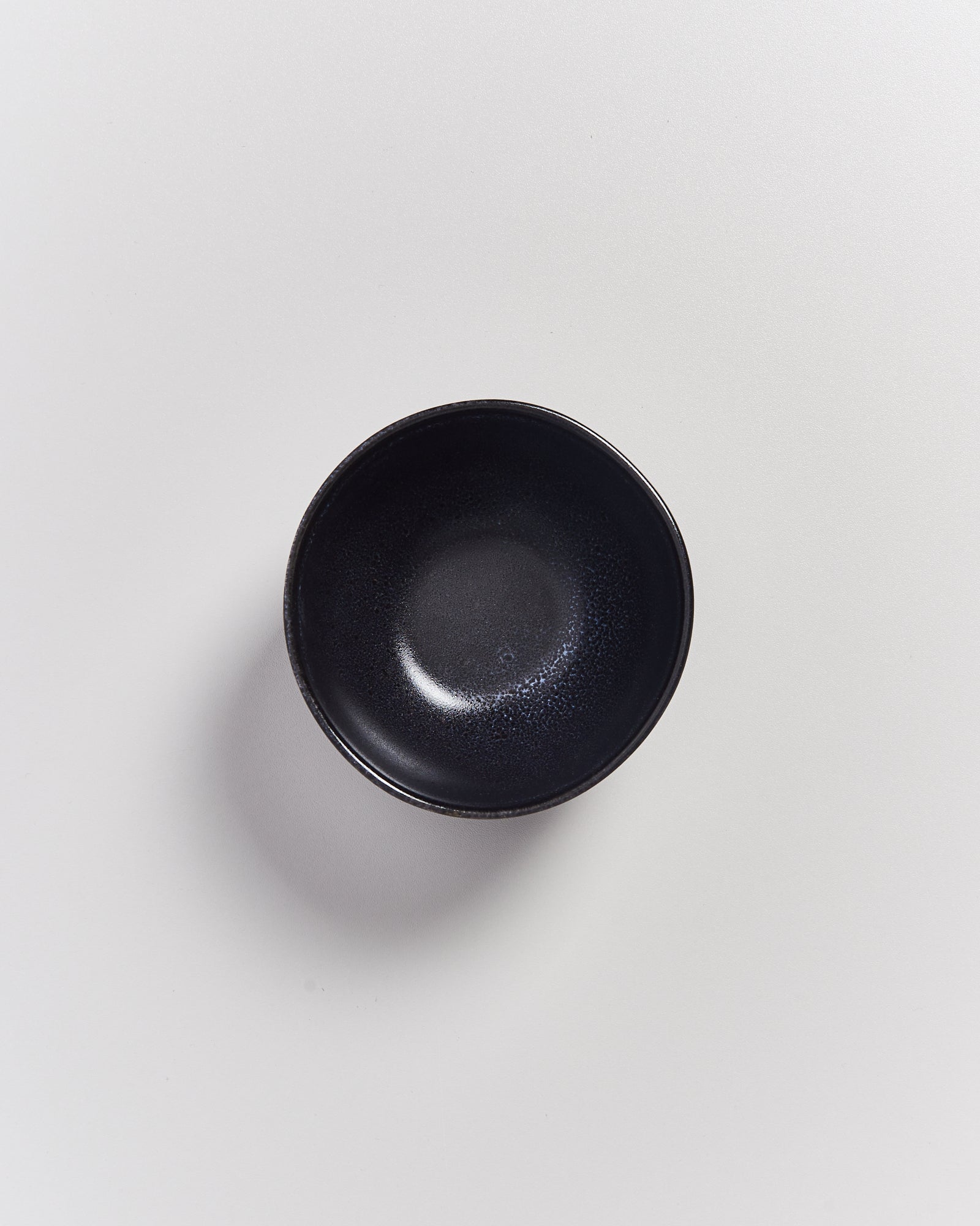 Schwarze Schale auf weißem Hintergrund, von oben betrachtet.