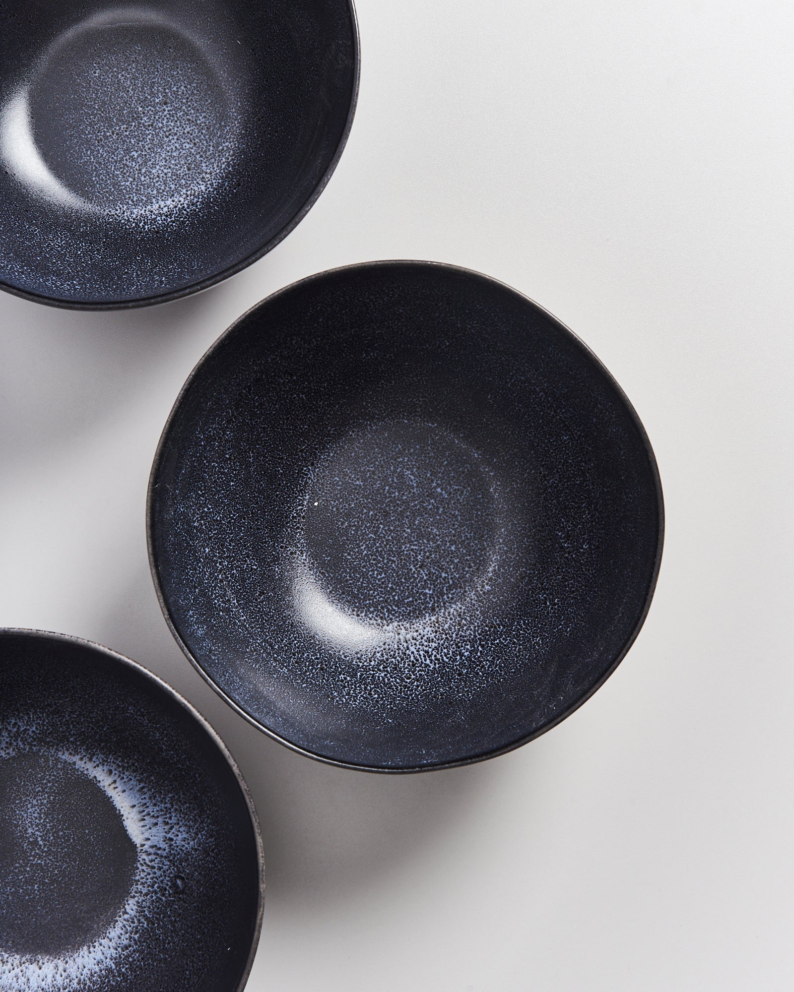 Drei schwarze Schalen mit leicht gesprenkelten Mustern auf einer hellen Oberfläche.