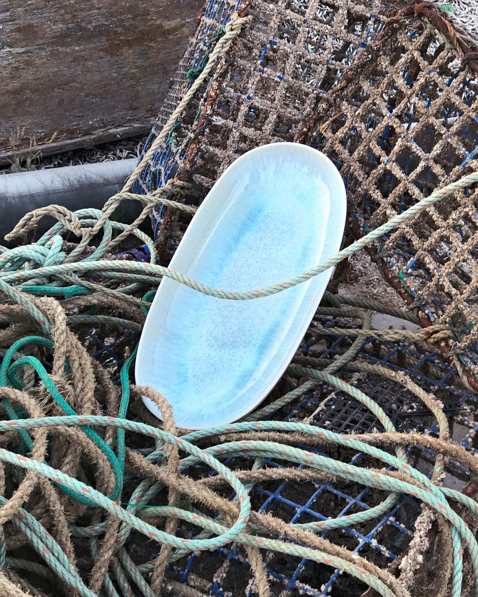 Ein blaues Porzellanboot liegt auf einem Netz und Seilen.