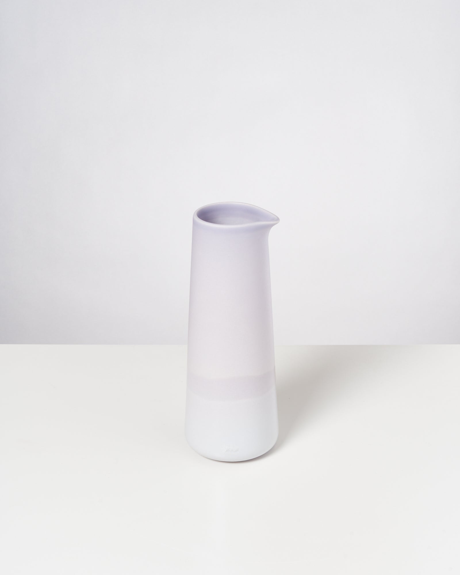 Hochformatiger, helllila Keramikkrug auf weißem Hintergrund.