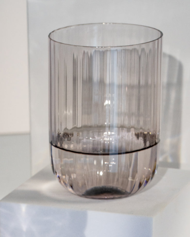 Ein durchsichtiges, geriffeltes Glas steht auf einem weißen Podest.