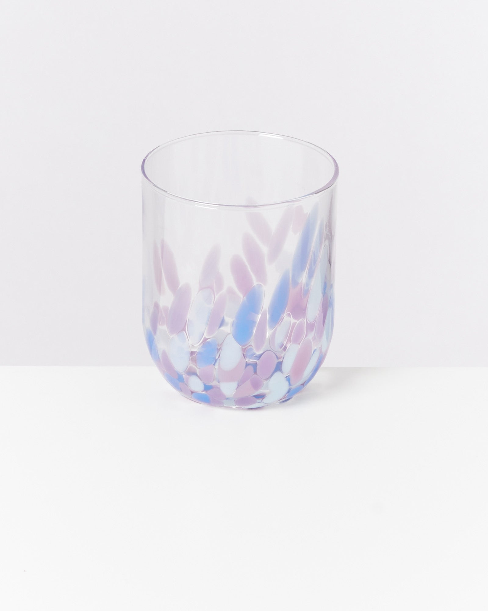 Transparenter Glasbecher mit violetten und blauen Mustern auf weißem Hintergrund.