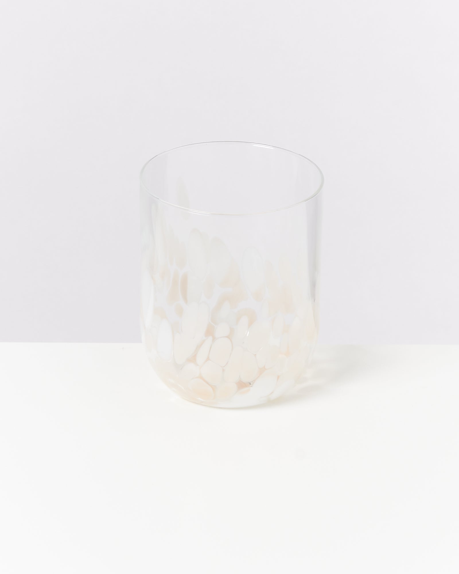 Transparenter Tumbler mit weißem, organischem Muster, auf weißem Hintergrund fotografiert.