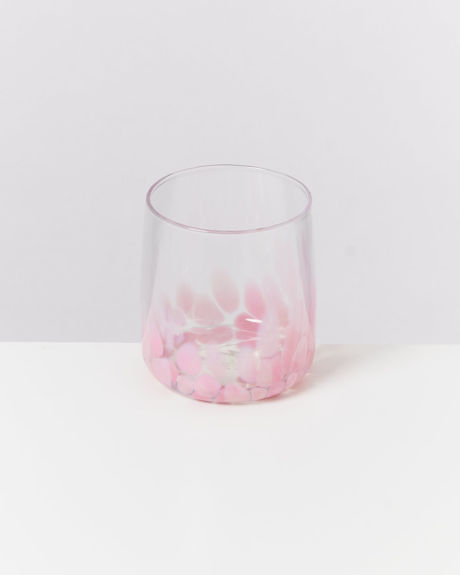 Ein Trinkglas mit rosa und transparenten Mustern auf einem weißen Hintergrund.