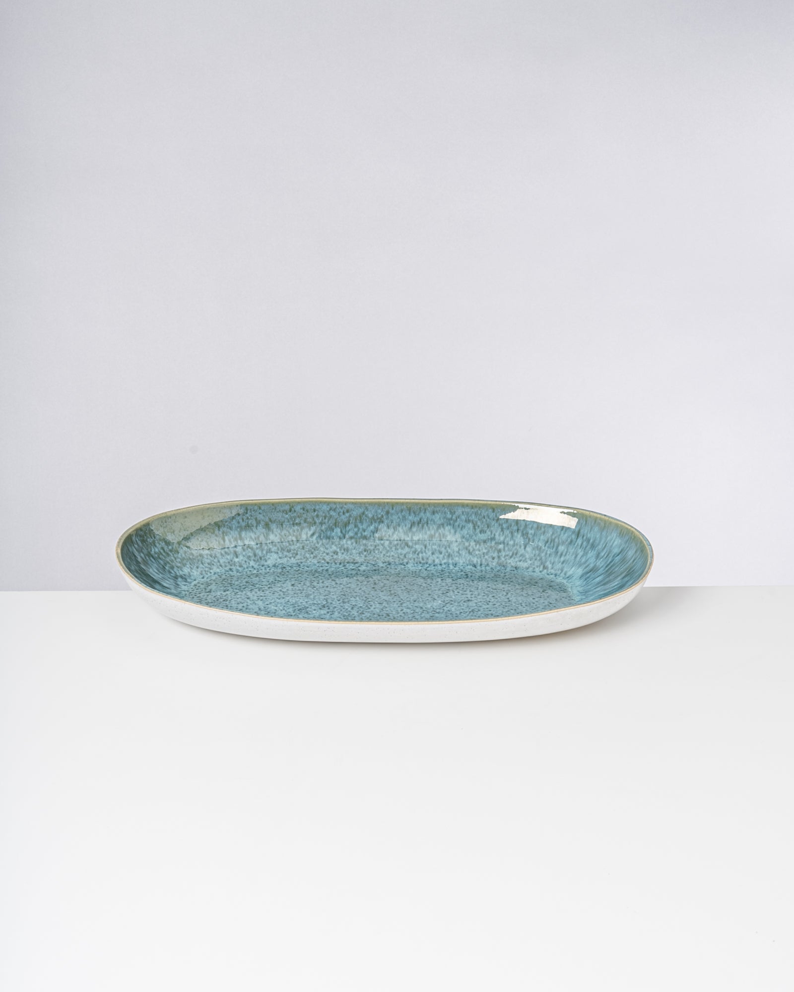 Ovaler Keramikteller mit blauem Innenbereich auf weißem Hintergrund.