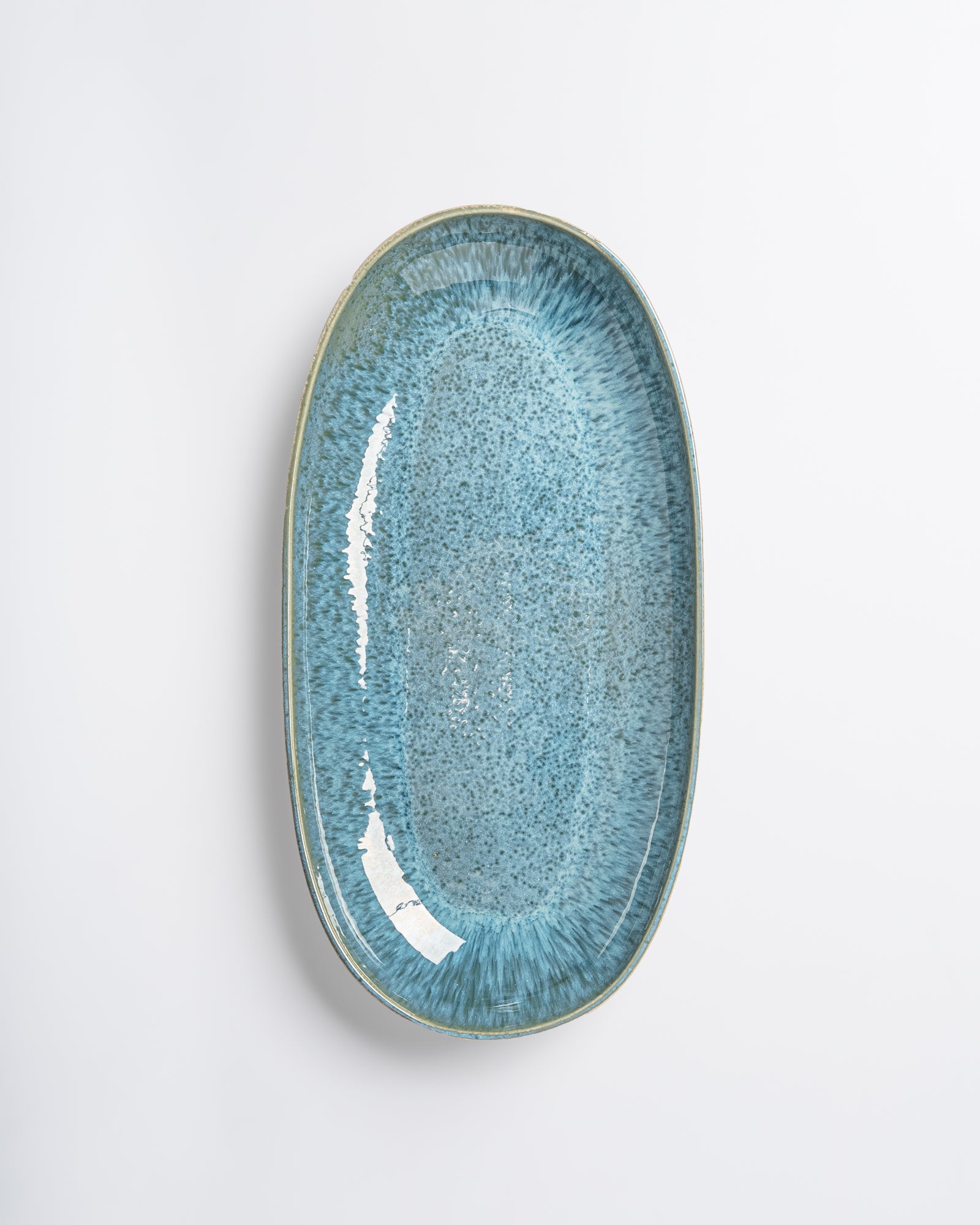 Ovale, himmelblaue Keramikplatte mit glatter, glänzender Oberfläche auf weißem Hintergrund.