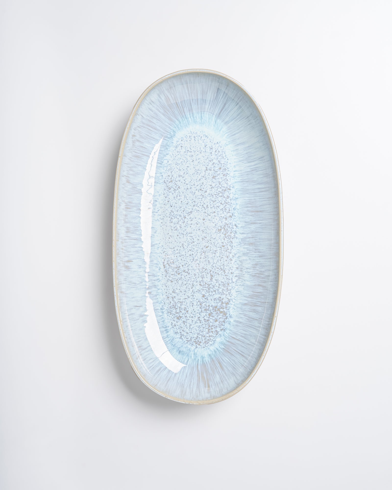 Ovale, hellblau glasierte Keramikplatte auf weißem Hintergrund.