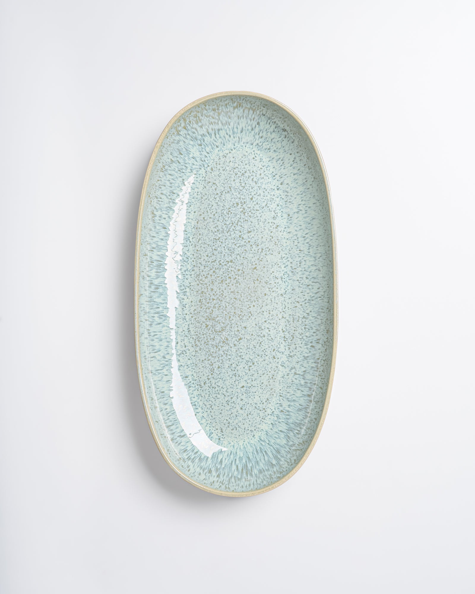 Ovaler, hellblauer Keramikteller mit gesprenkeltem Muster auf weißem Hintergrund.