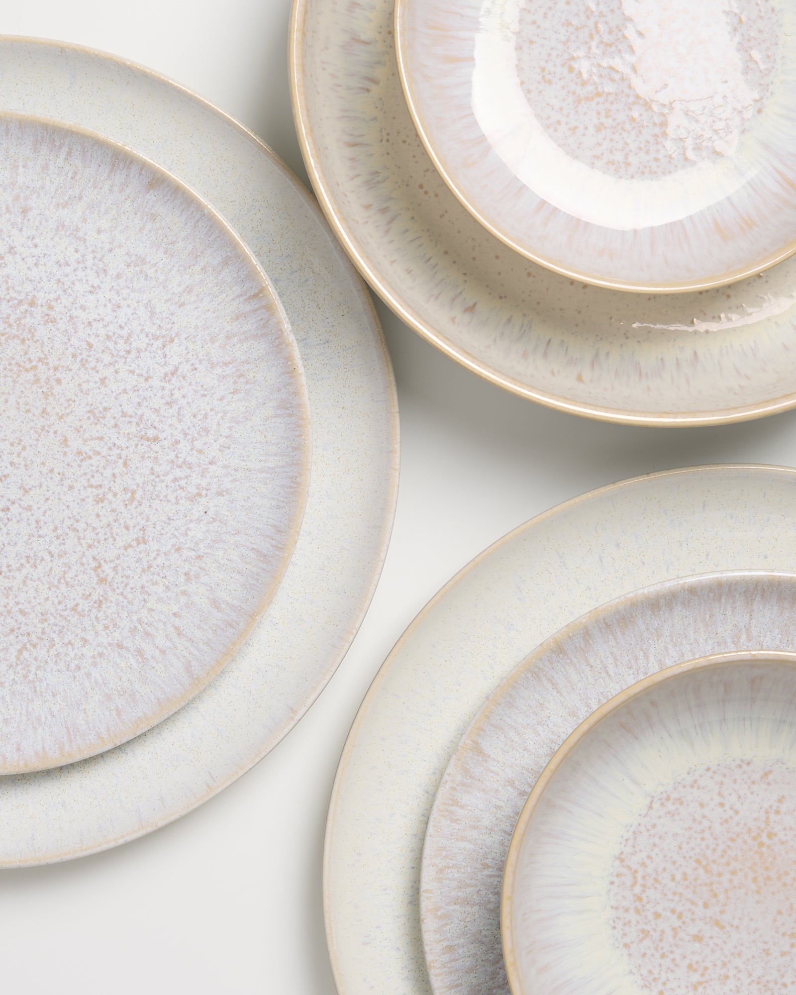 Nahaufnahme von mehreren hellen, strukturierten Keramiktellern übereinander angeordnet.