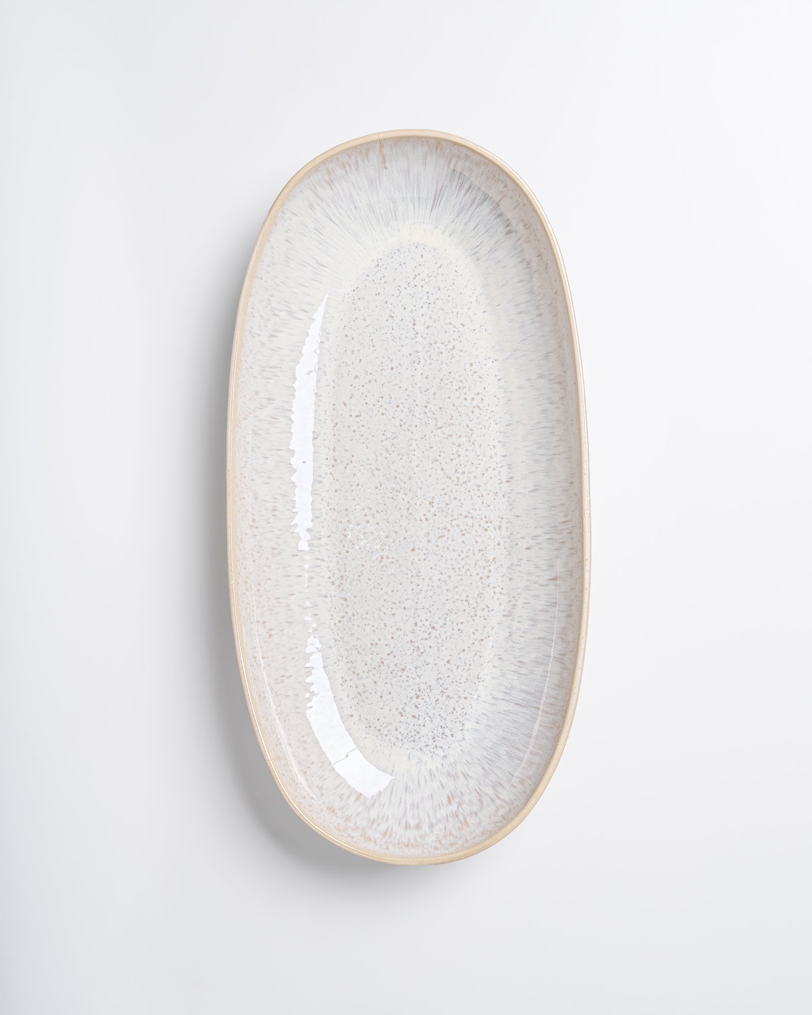 Ovaler, cremefarbener Keramikteller mit dezentem Muster auf einem weißen Hintergrund.