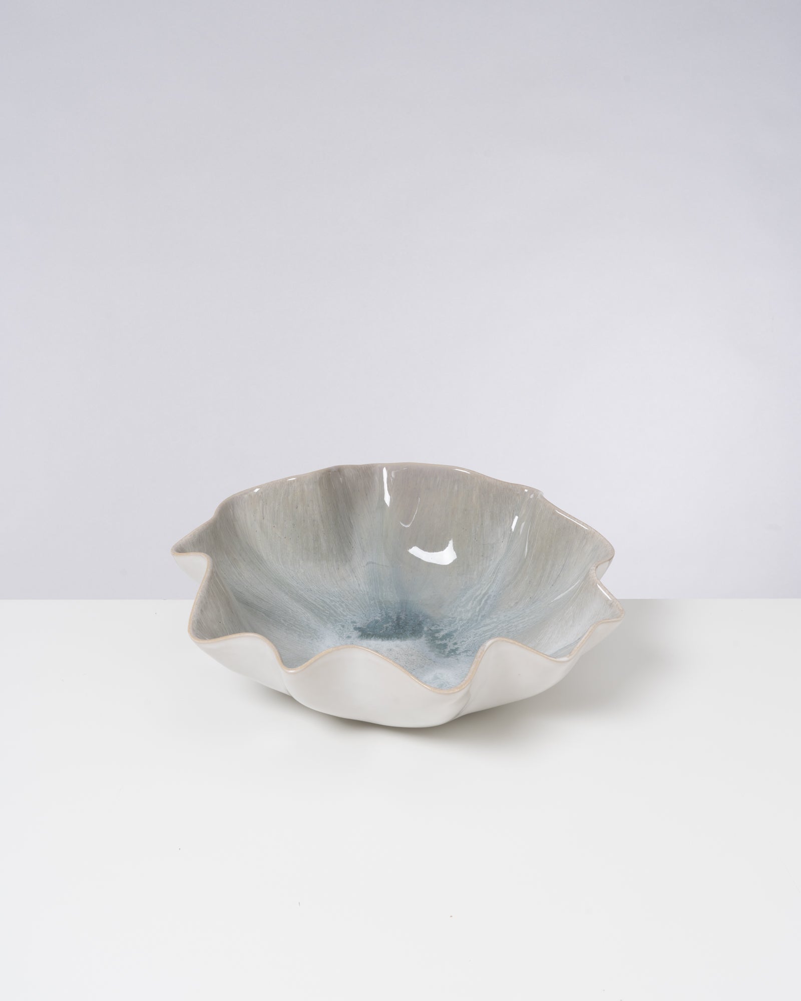 Keramikschale mit welligem Rand und hellblauer Glasur auf weißem Hintergrund.