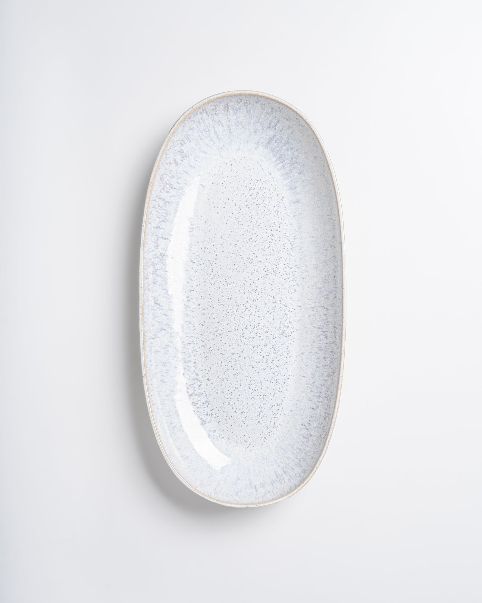Ovaler, weißer Keramikteller mit gesprenkeltem Muster auf weißem Hintergrund.