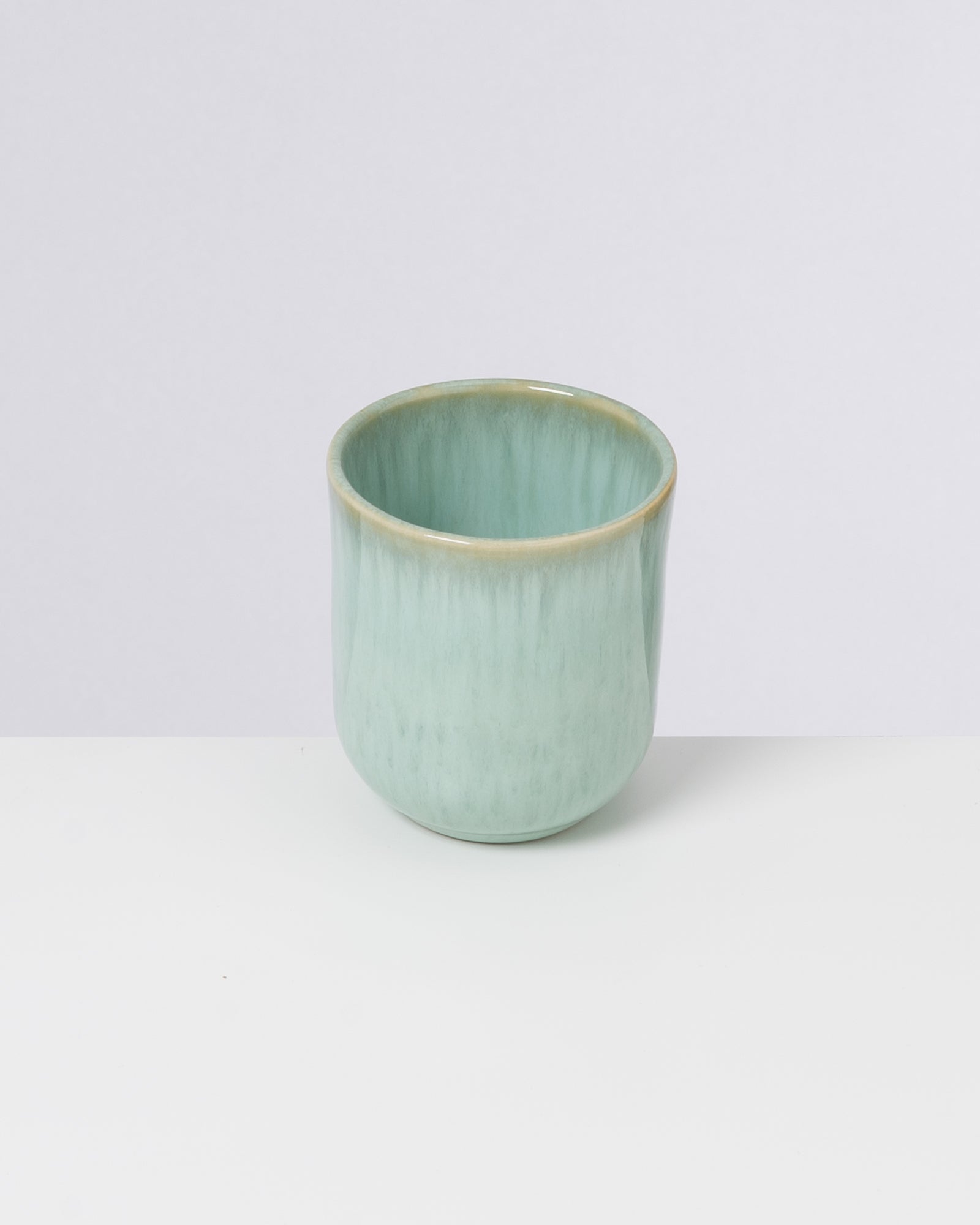 Grüne Keramiktasse auf weißem Hintergrund.