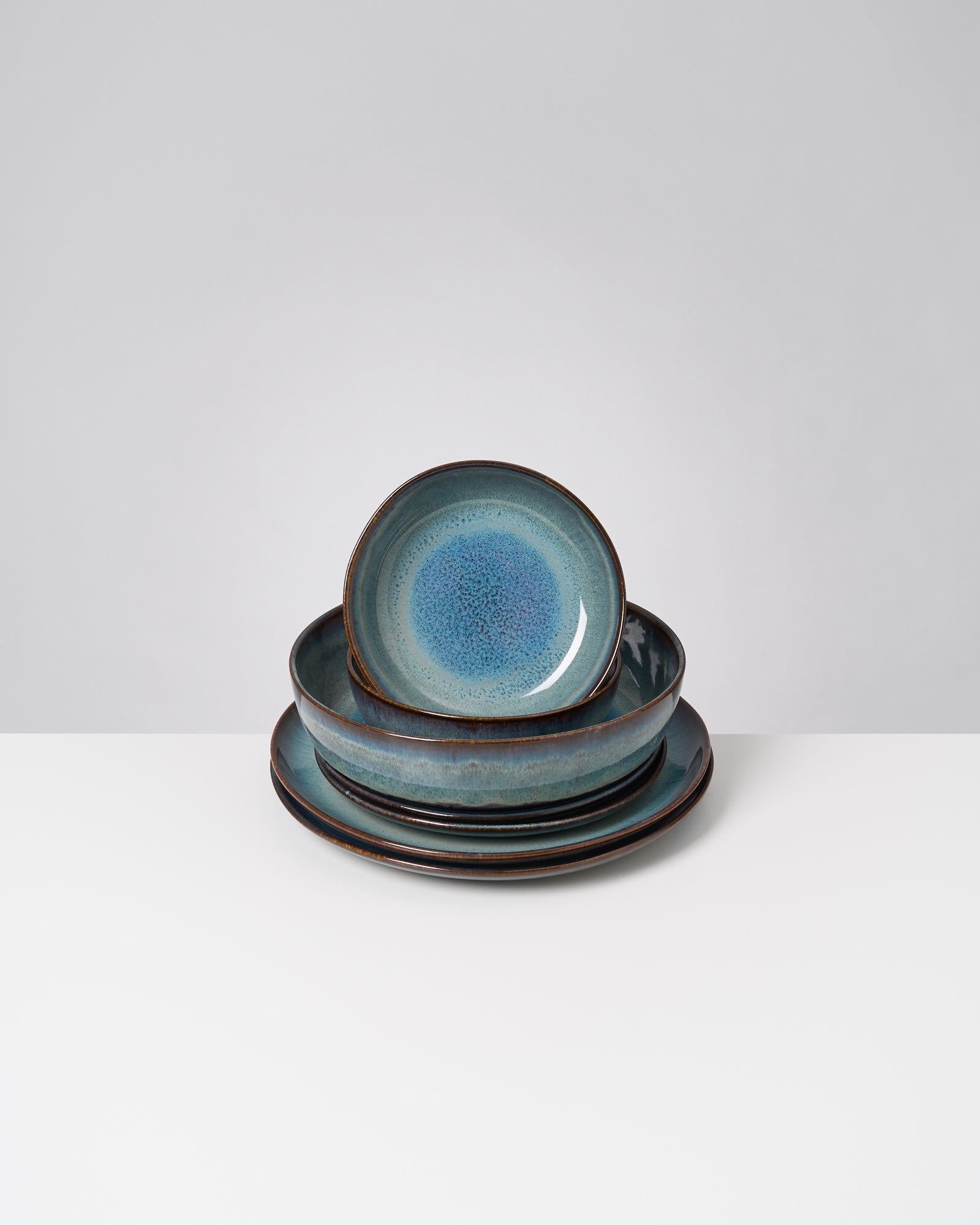Ein Stapel blauer Keramikteller, Schüsseln und Schalen auf einem weißen Hintergrund.