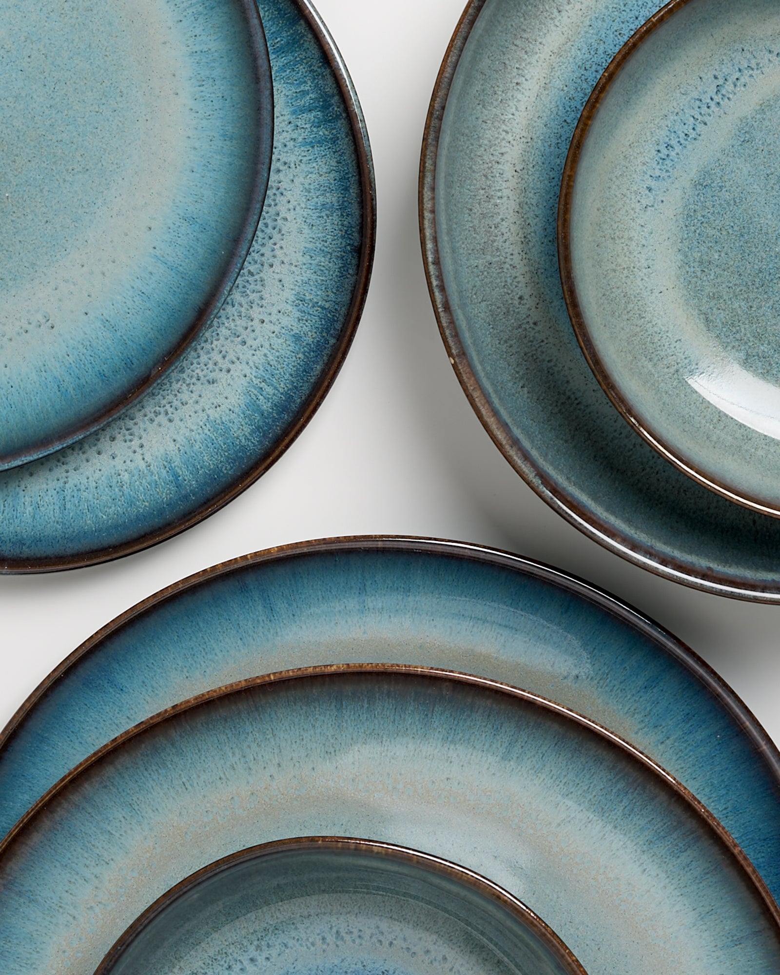 Mehrere blaue Keramikteller mit einem Verlaufsmuster auf einem weißen Hintergrund.