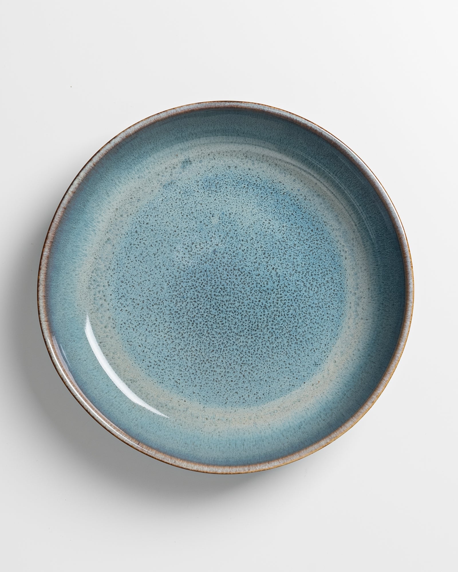 Blauer Keramikteller mit gesprenkeltem Muster auf weißem Hintergrund.