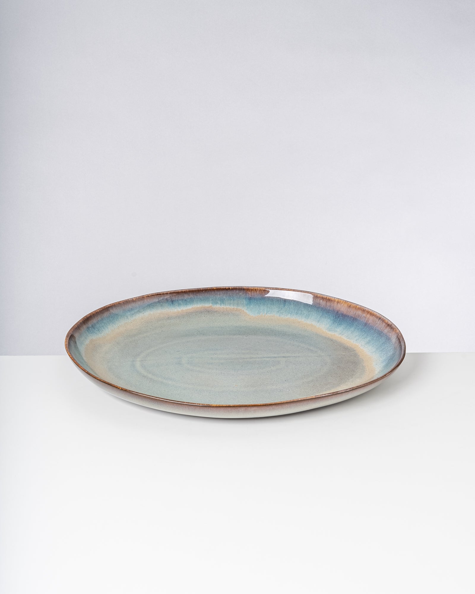 Keramikteller mit blau-braunen, verlaufenden Glasuren auf einem weißen Hintergrund.