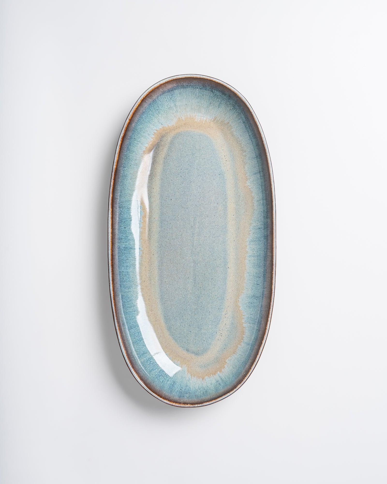 Ein ovaler Keramikteller mit bläulichem Farbverlauf auf weißem Hintergrund.