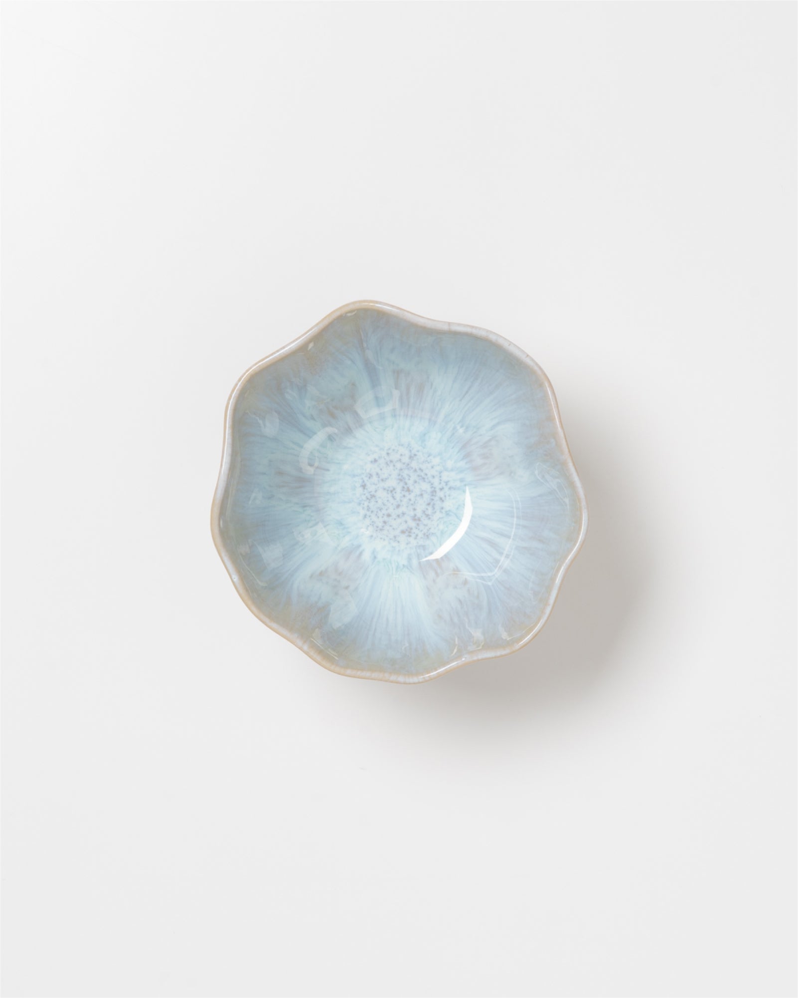 Kleiner blauer Keramikschale mit unregelmäßigem Rand auf weißem Hintergrund.