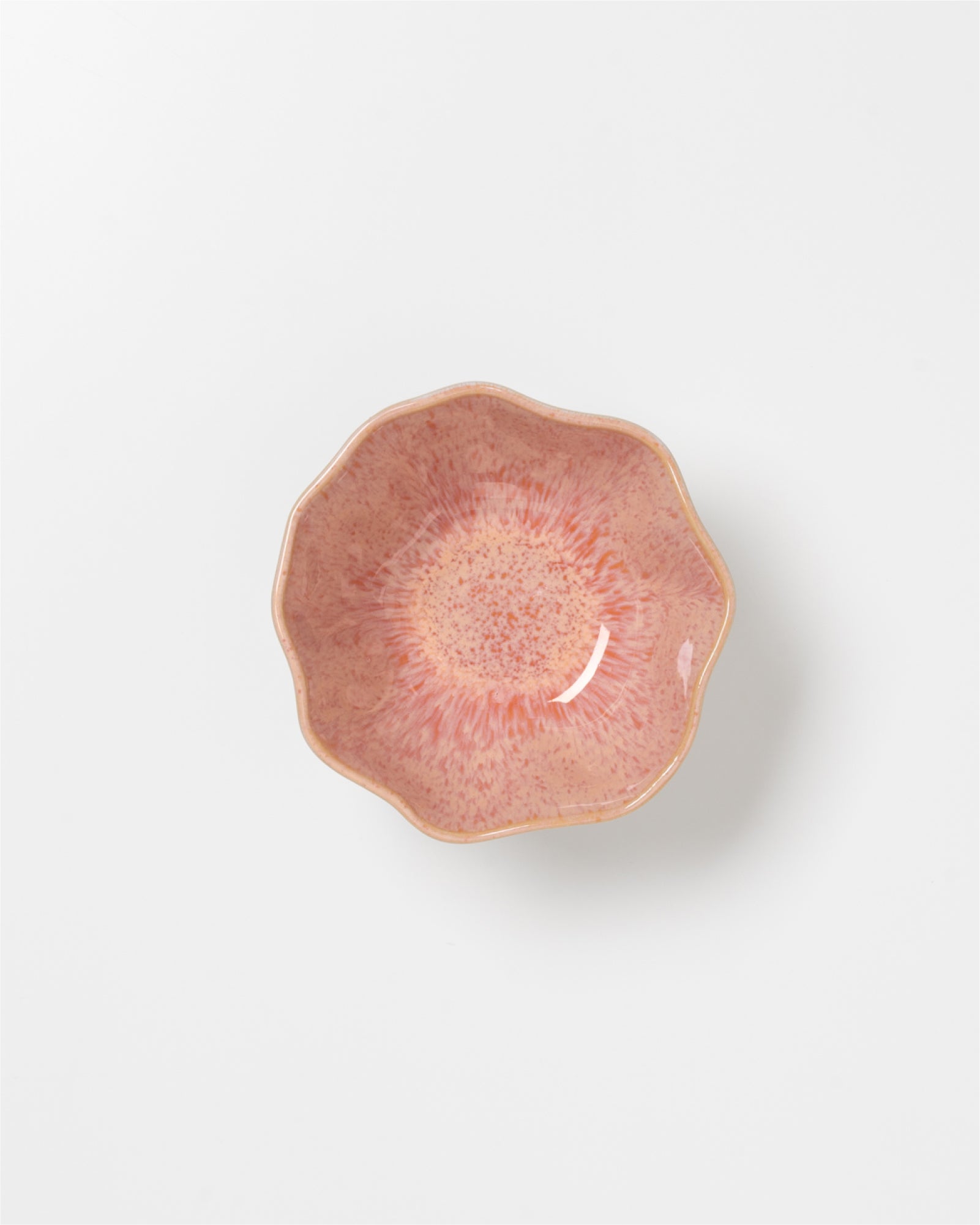 Rosafarbene, blumenförmige Schale mit glasiertem, gesprenkeltem Muster auf weißem Hintergrund.