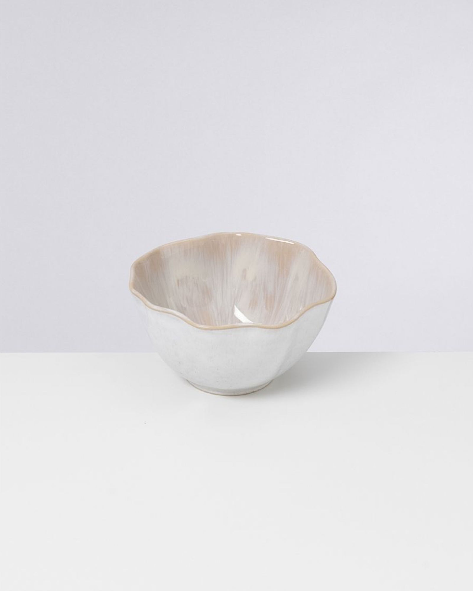 Weiße, blütenförmige Keramikschale mit glänzender, beiger Innenseite auf hellem Hintergrund.