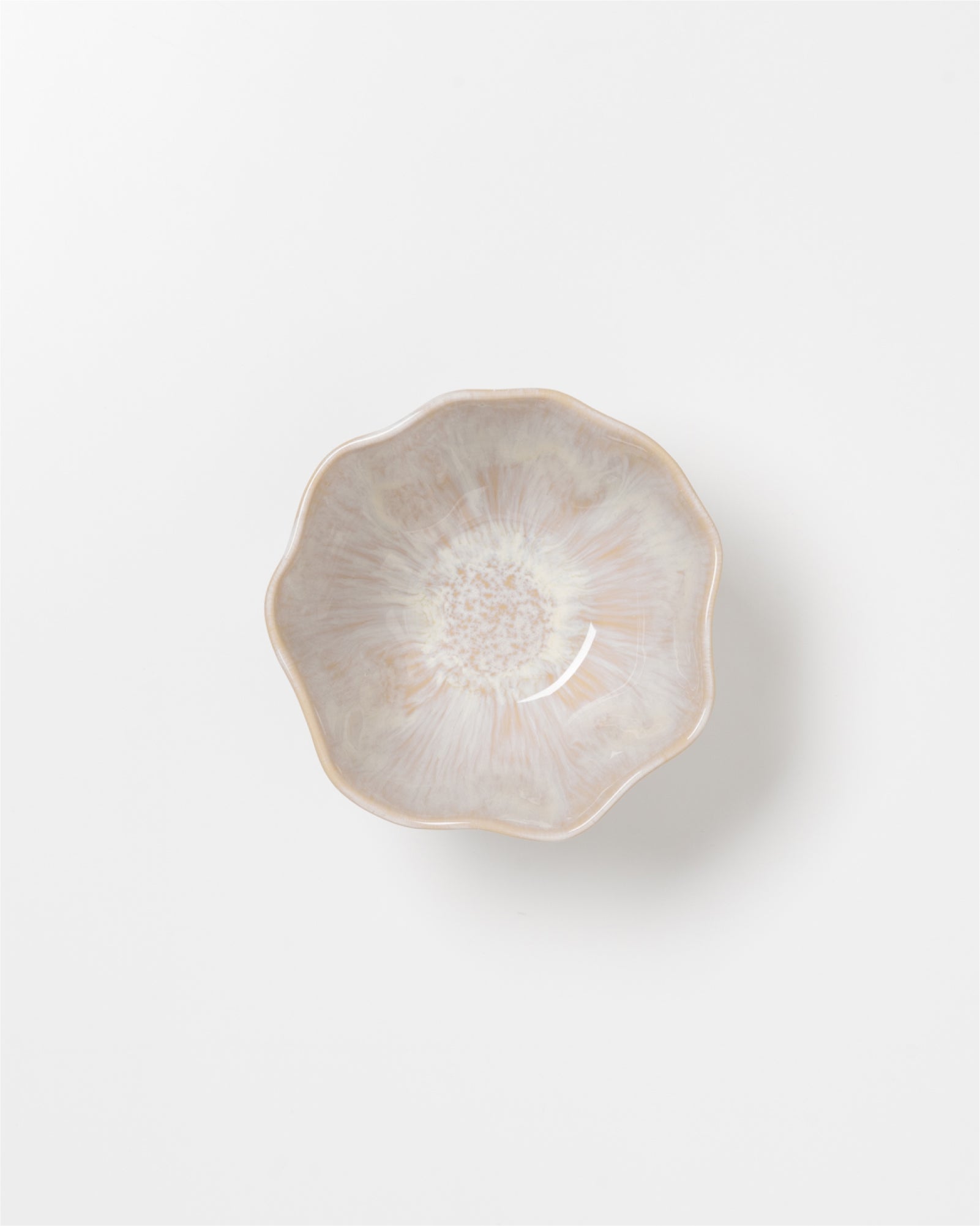 Keramikschale mit blumenförmigem Rand und heller, gemusterter Glasur auf weißem Hintergrund.