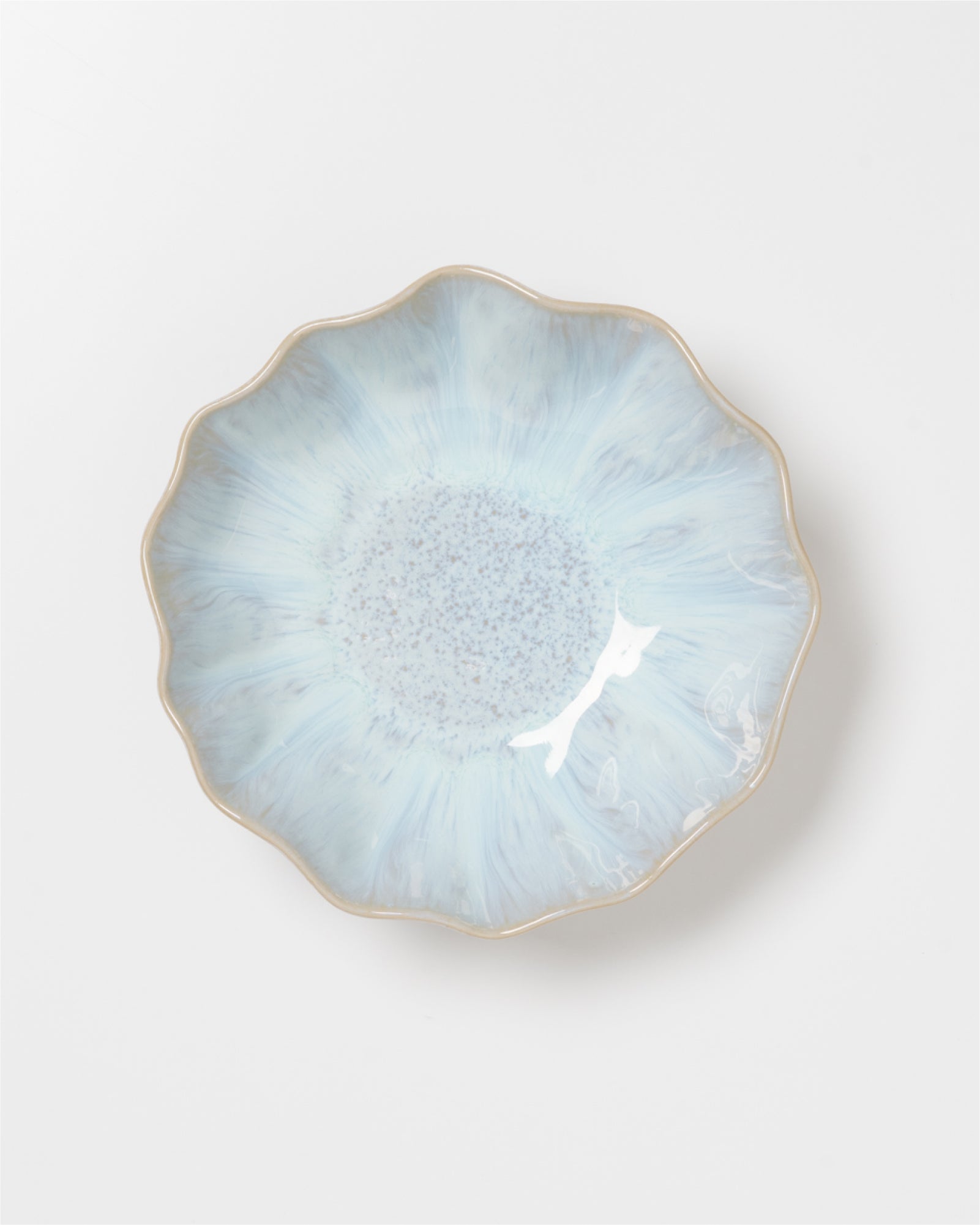 Erhelle Porzellanschale mit blauer, blütenähnlicher Glasur und gewelltem Rand auf weißem Hintergrund.