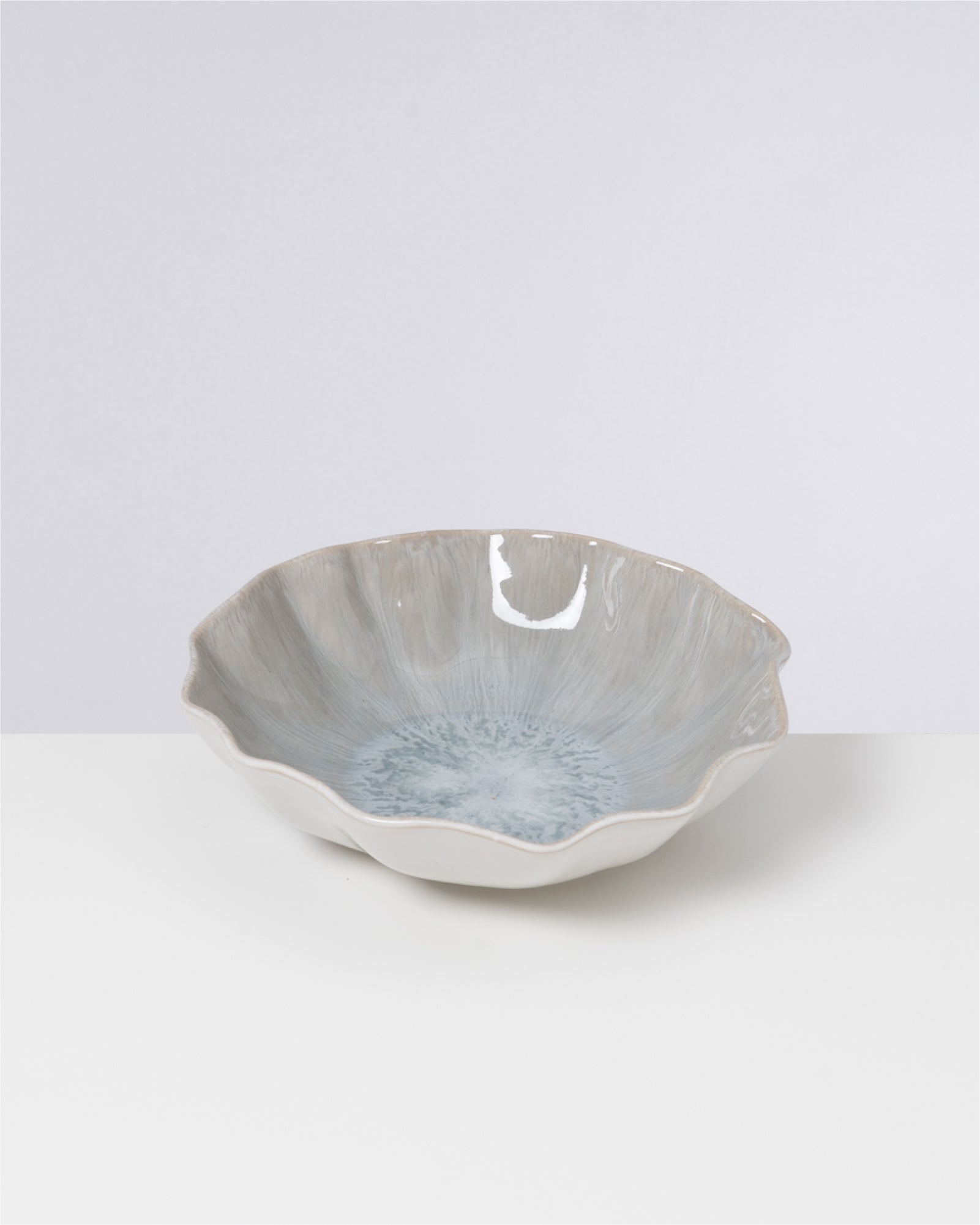 Keramikschale mit unregelmäßiger Form und bläulichem Muster im Inneren auf hellem Hintergrund.