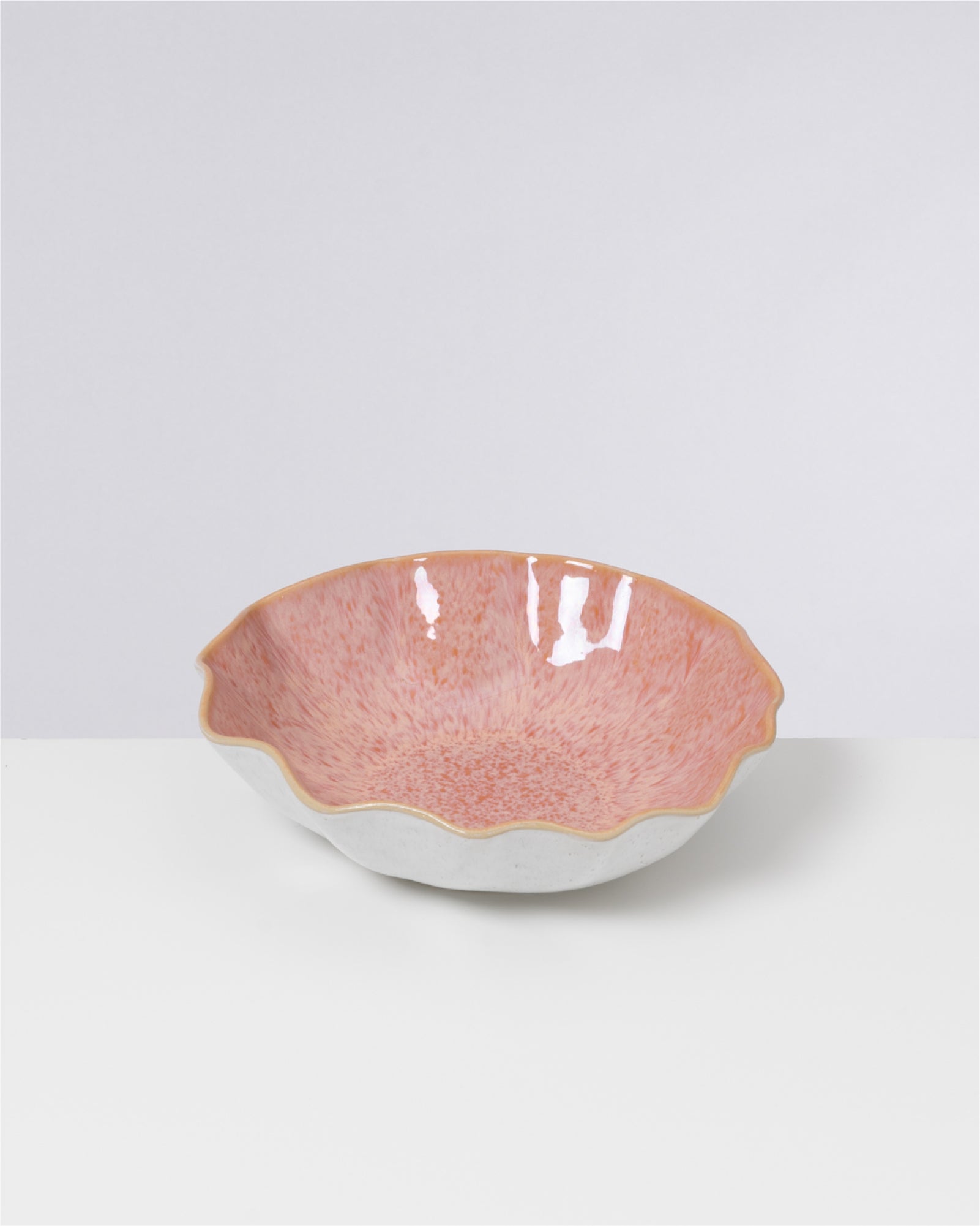 Rosafarbene, runde Schale mit welligem Rand auf weißem Hintergrund.