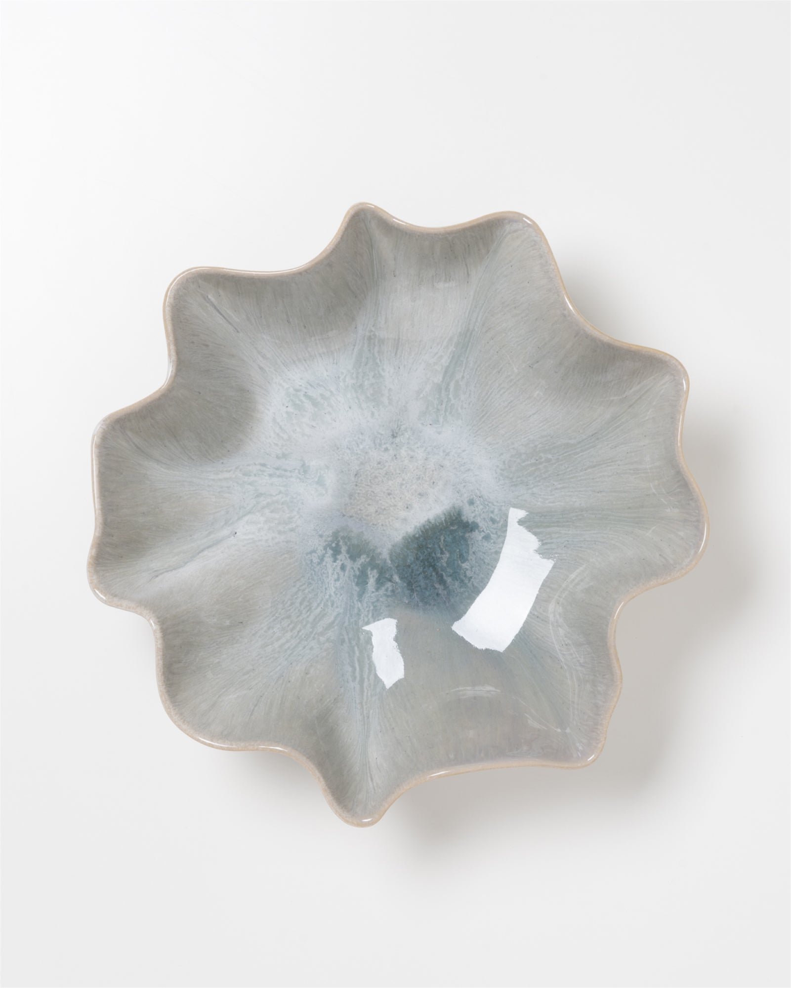 Graue Keramikschale mit unregelmäßig gewelltem Rand auf weißem Hintergrund.