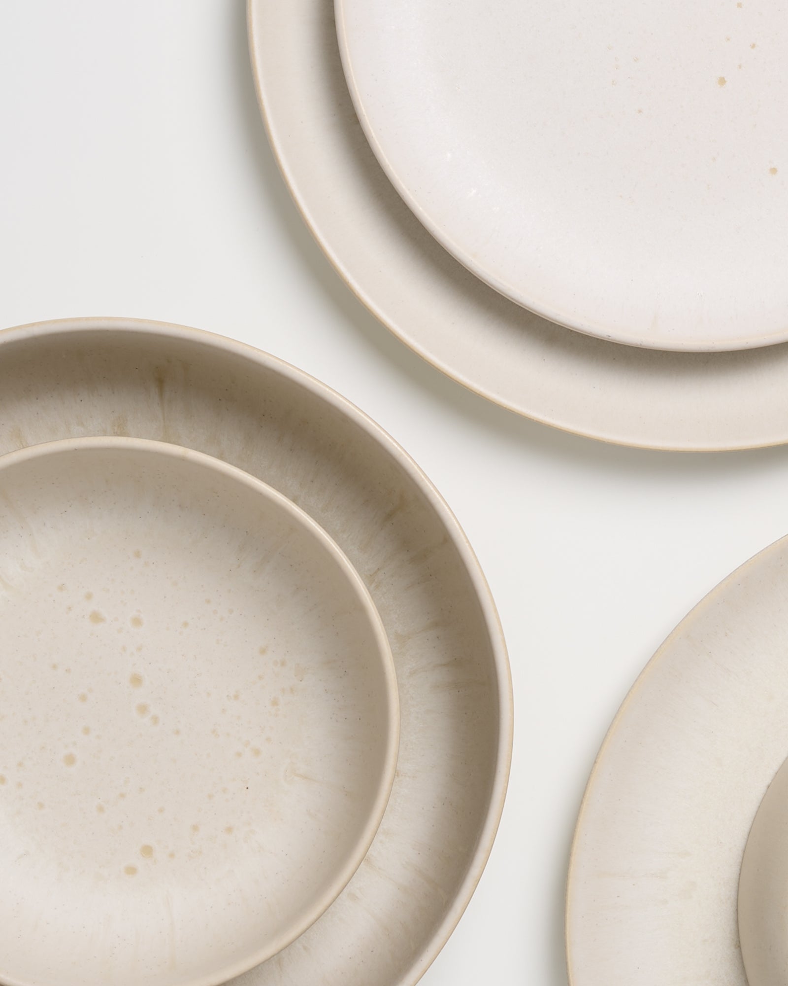 Drei beige Keramikteller in verschiedenen Größen liegen auf einem weißen Hintergrund.