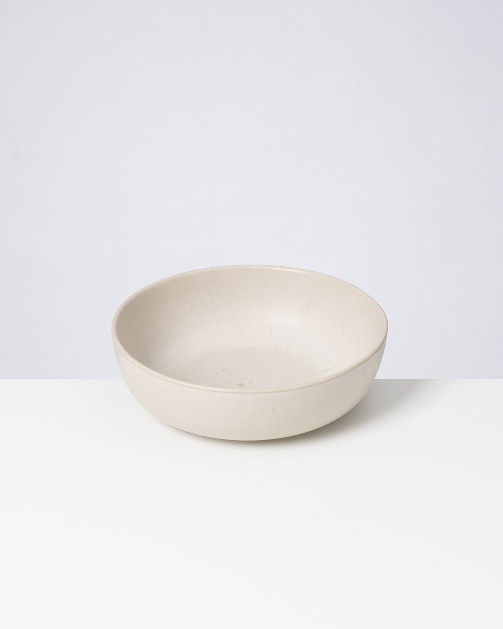 Beige Schüssel auf einem weißen Untergrund vor einem hellgrauen Hintergrund.