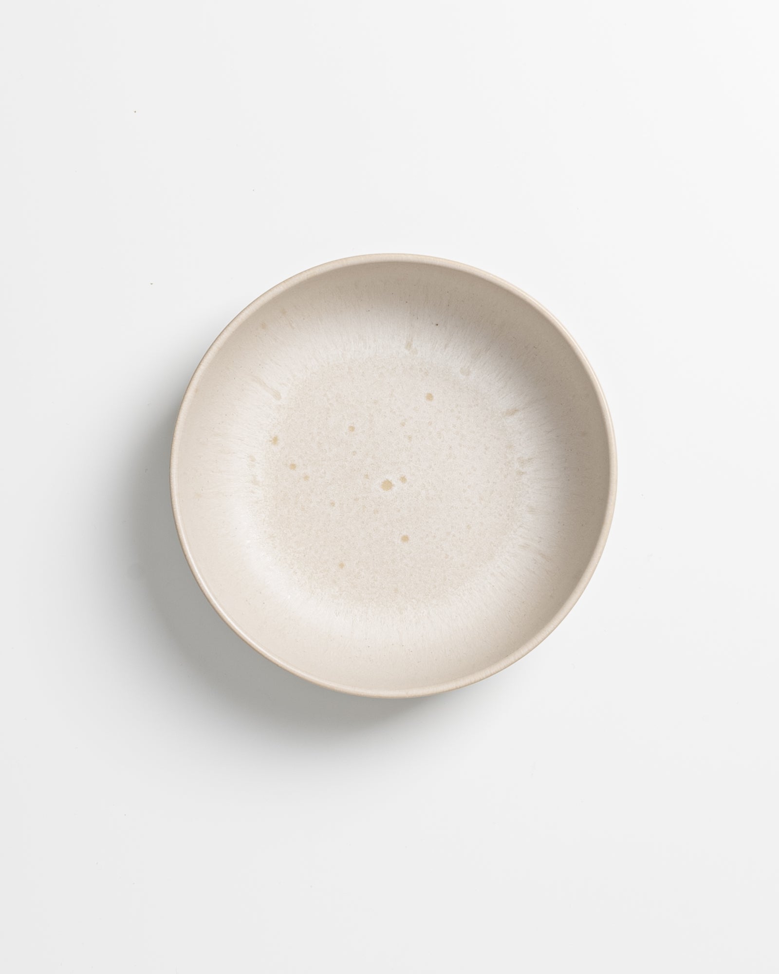 Beiger, minimalistischer Keramikteller auf weißem Hintergrund.